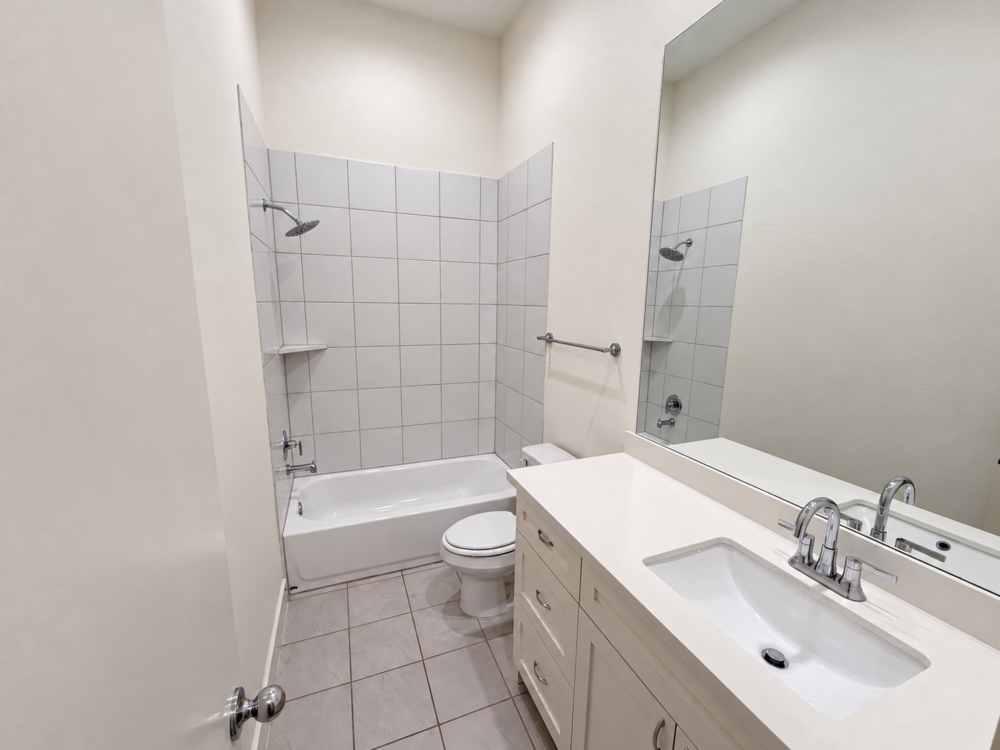 Downstairs bathroom featuring a spacious vanity and a tiled tub and shower combination.