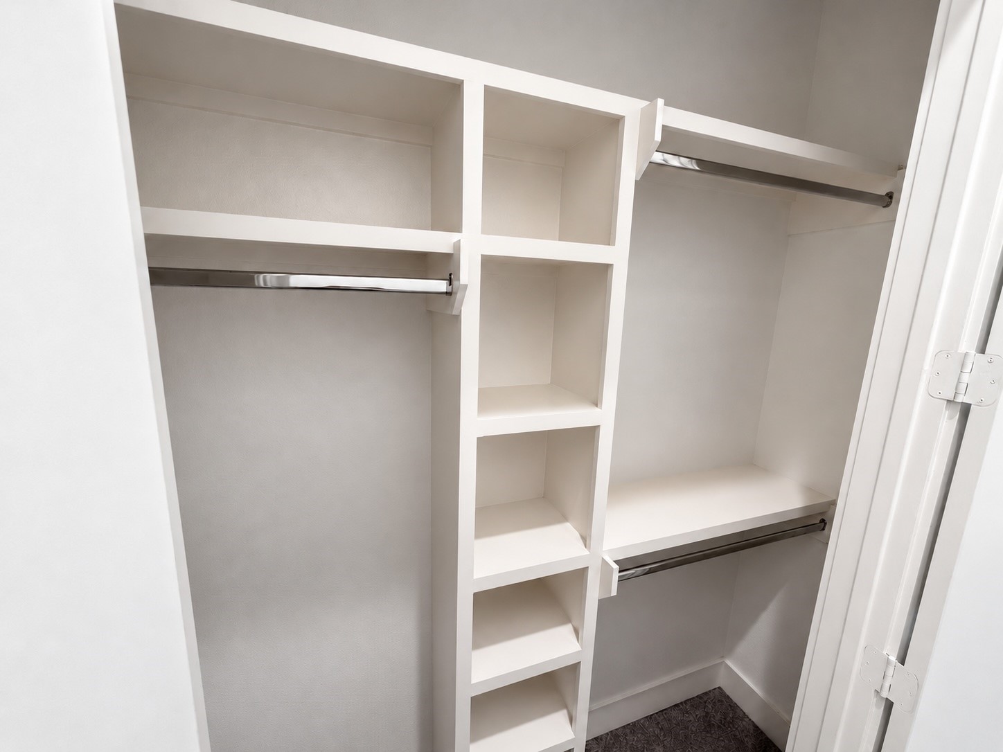 Downstairs bedroom closet with built-in shelving and ample hanging space.