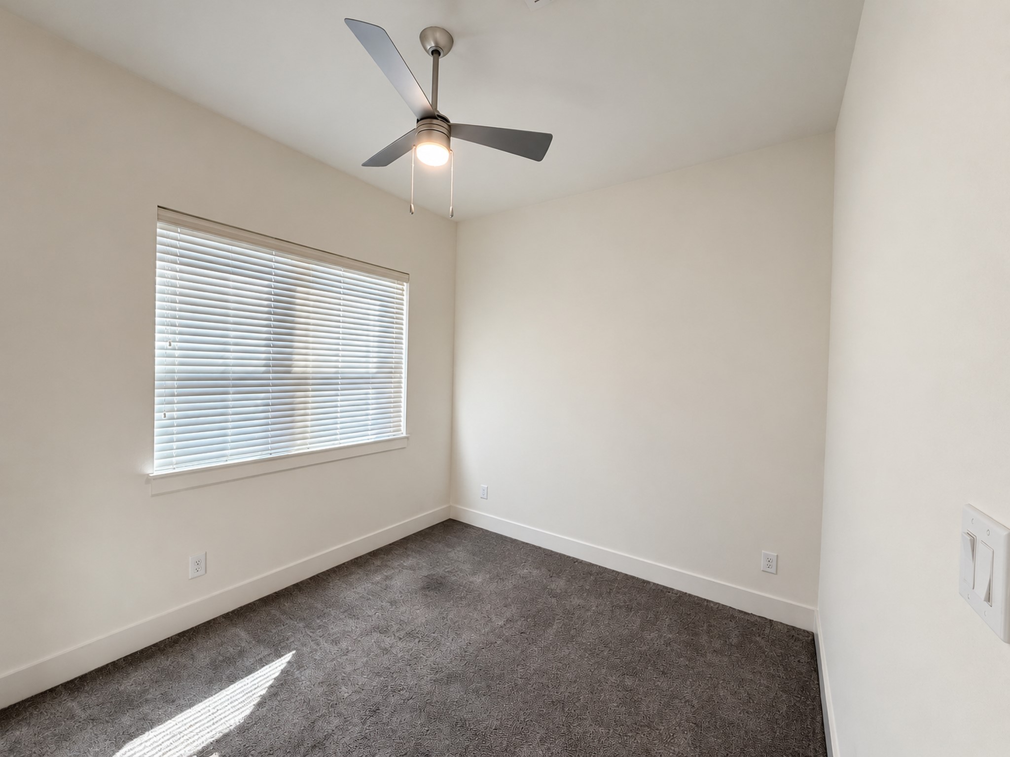Inviting second-floor bedroom with soft carpeting, natural light, and a ceiling fan.