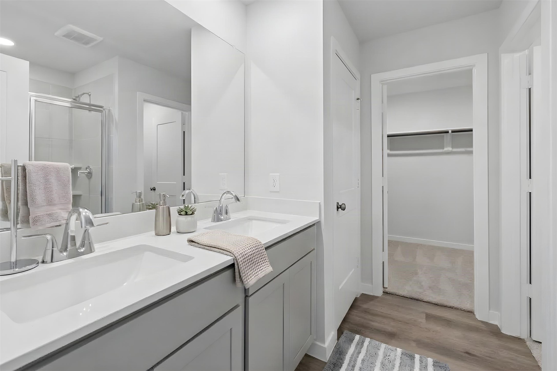 Experience luxury in the primary bath, featuring a sleek double vanity, elegant fixtures, and seamless access to a spacious walk-in closet.