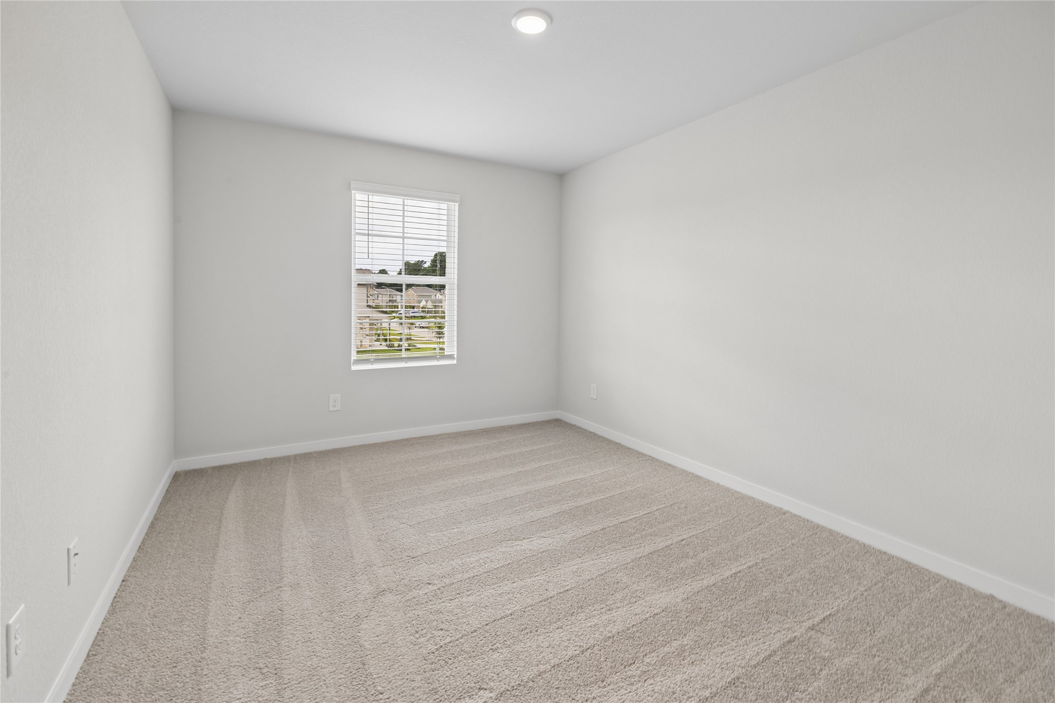 Bright and inviting bedroom with soft carpeting and a large window providing natural light.