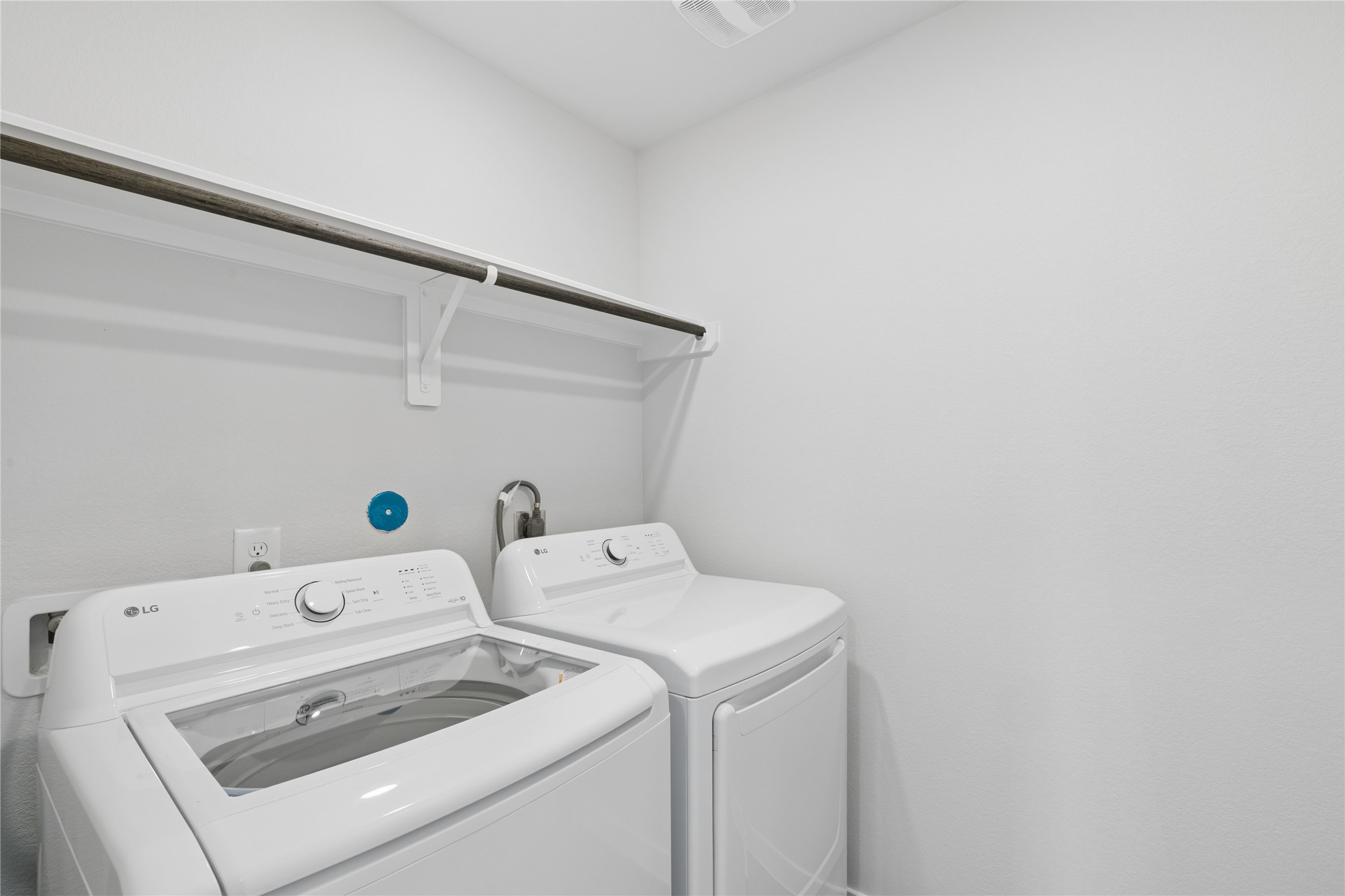 Effortlessly manage your laundry in this bright, organized space featuring modern washer and dryer with convenient shelving for all your essentials.