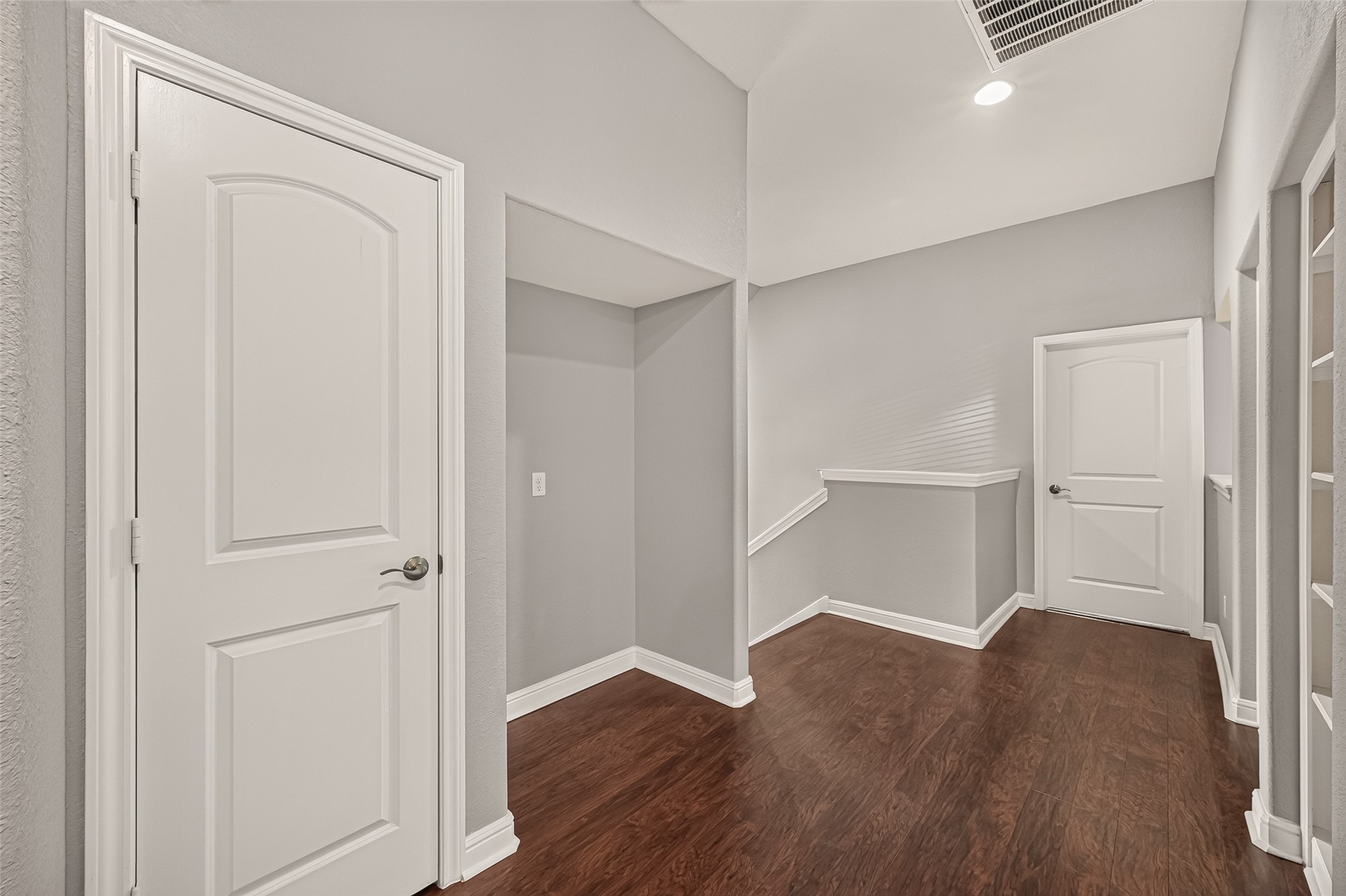 Bright and spacious hallway with elegant hardwood floors, neutral gray walls, and modern white doors, offering a welcoming and sophisticated entrance.
