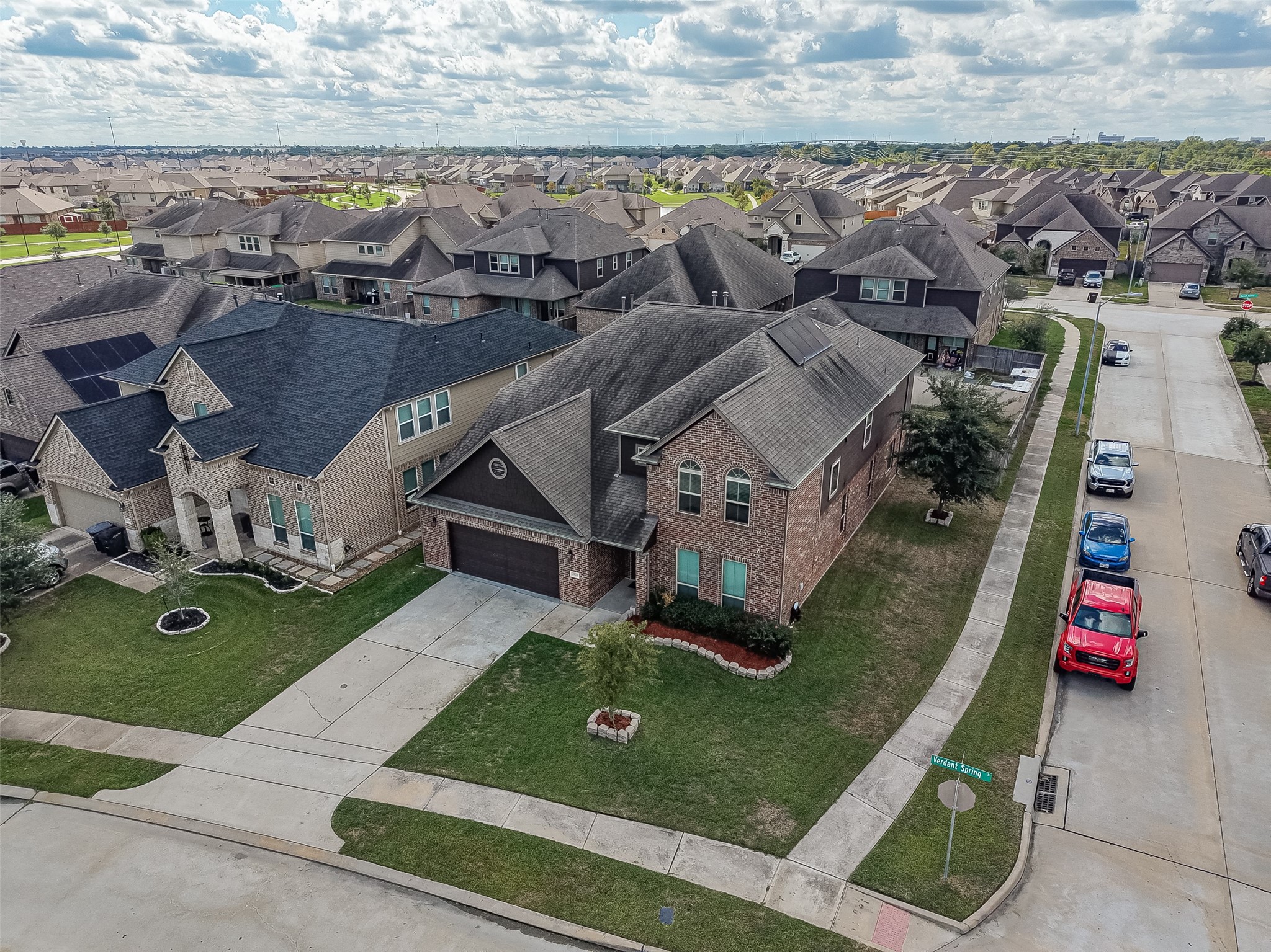 Charming two-story brick home on a spacious corner lot in a well-maintained neighborhood, featuring a two-car garage and lush green lawn.