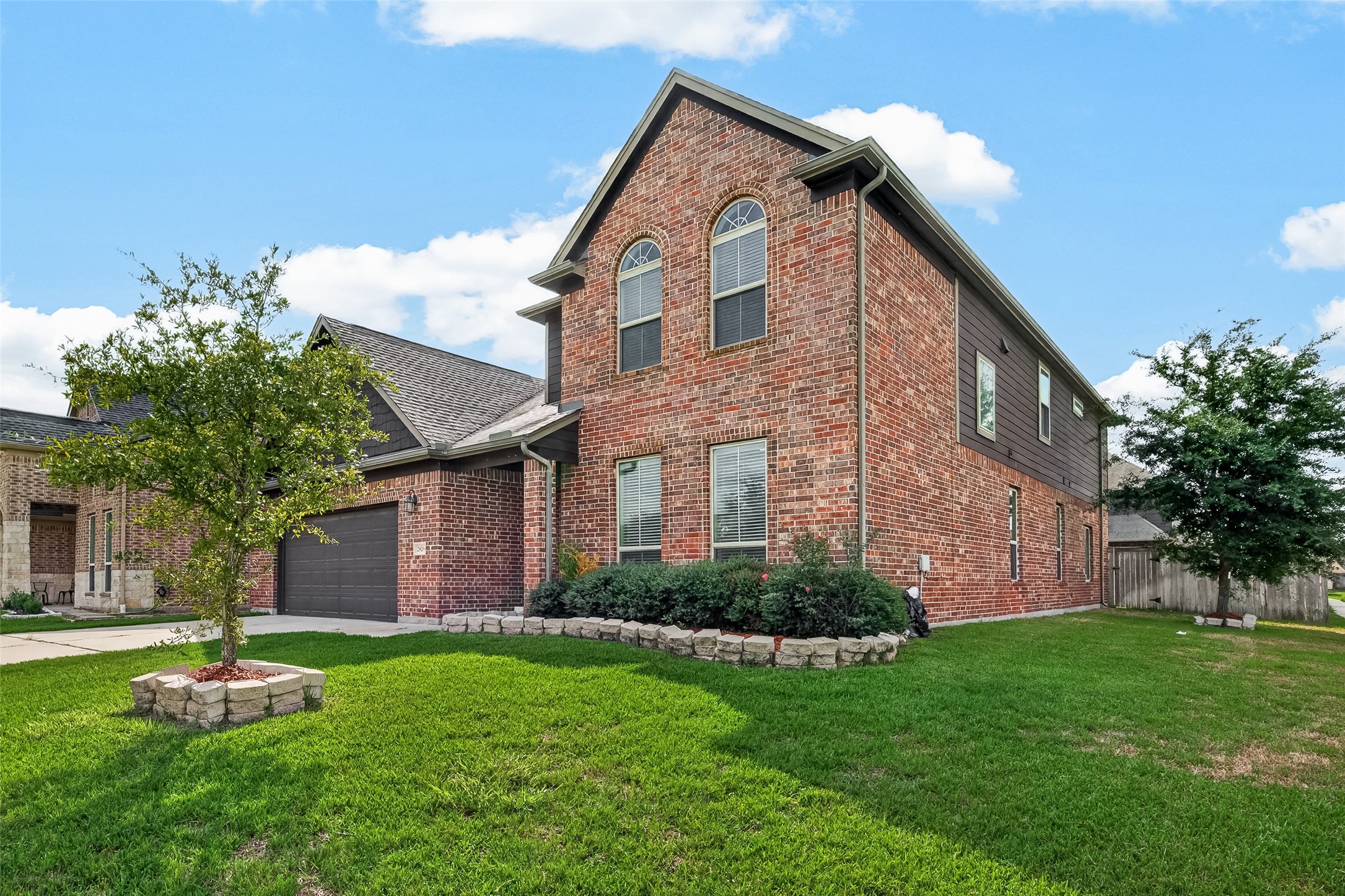 Stunning two-story brick home with charming curb appeal, featuring a landscaped front yard, a spacious driveway, and a two-car garage.