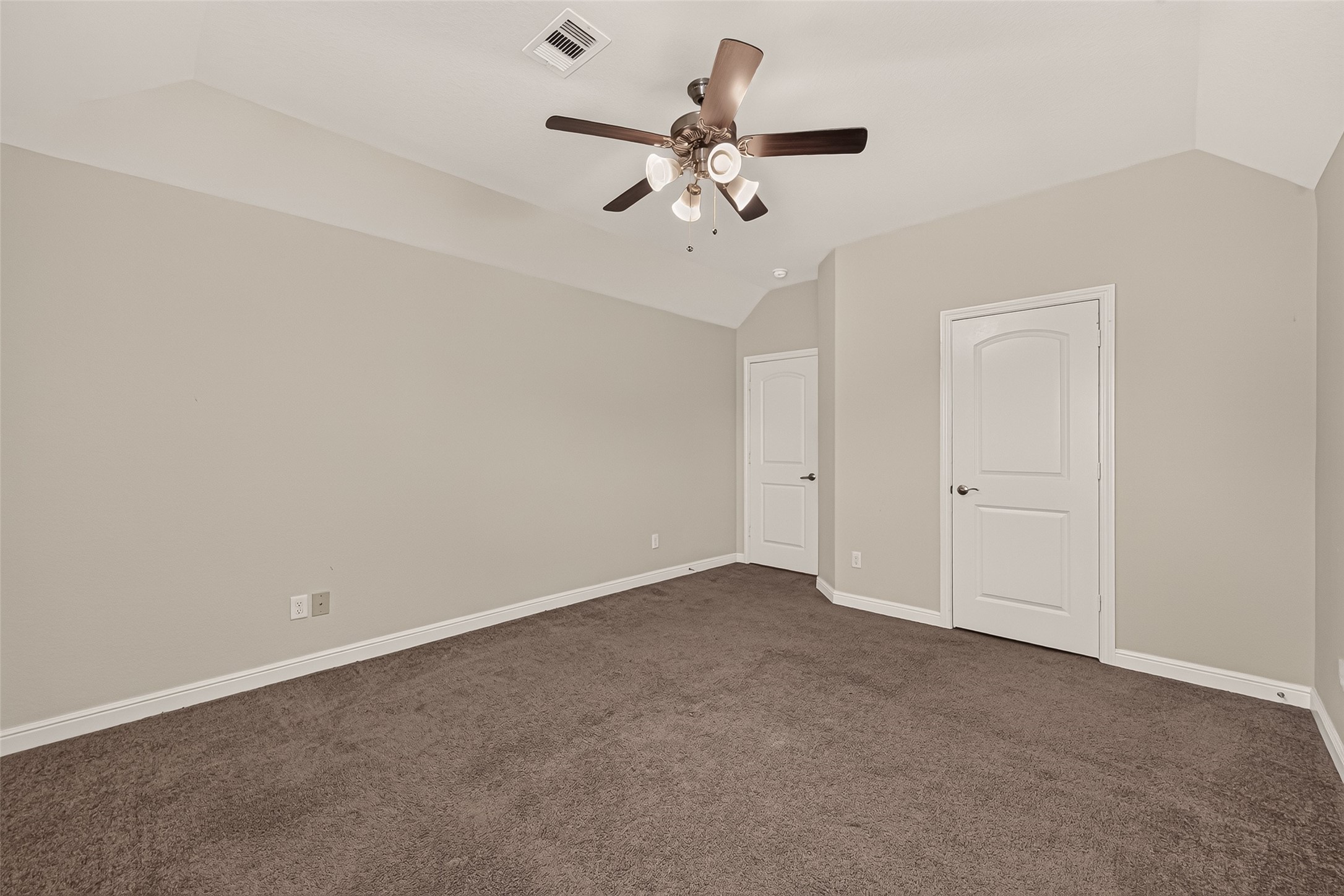 Spacious bedroom with neutrSpacious third bedroom with plush carpeting, neutral tones, a ceiling fan, abundant natural light, and dual closets.al walls, plush carpeting, and a stylish ceiling fan, offering comfort and modern elegance.