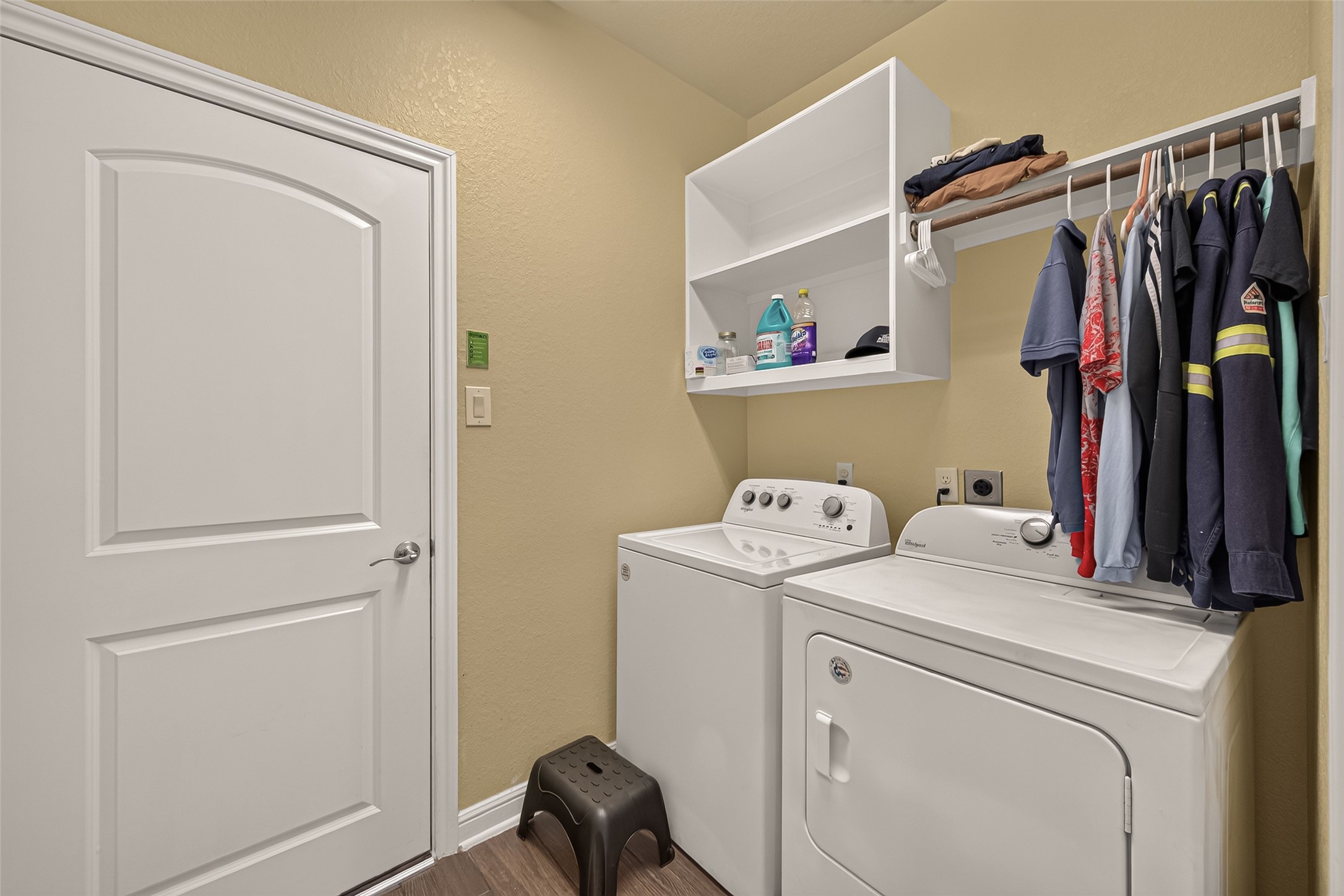Efficient laundry room with a washer and dryer, open shelving for storage, and a convenient hanging rod for clothes.