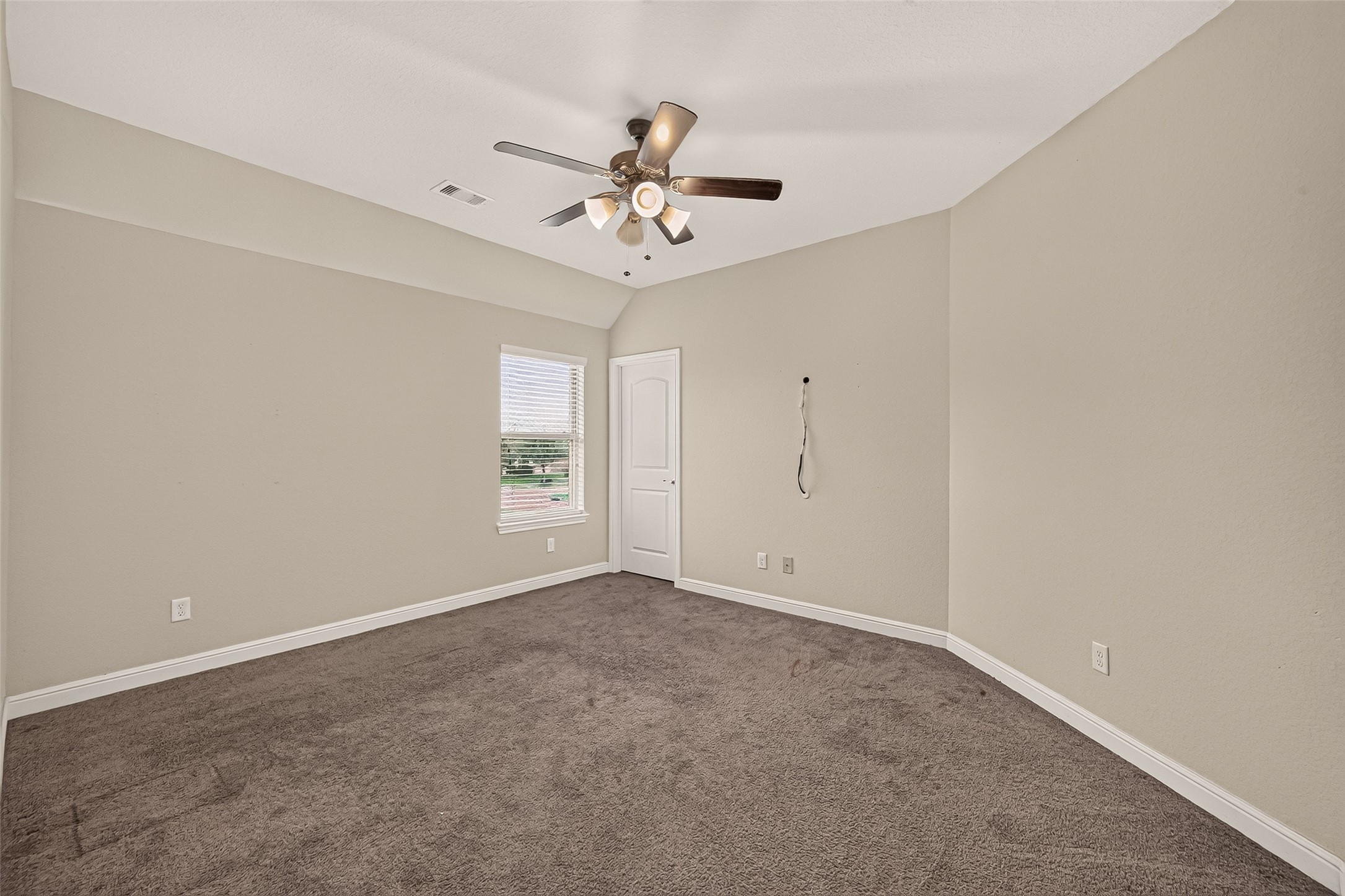 Spacious fifth bedroom featuring plush carpeting, a modern ceiling fan, and abundant natural light, creating a warm and inviting retreat.
