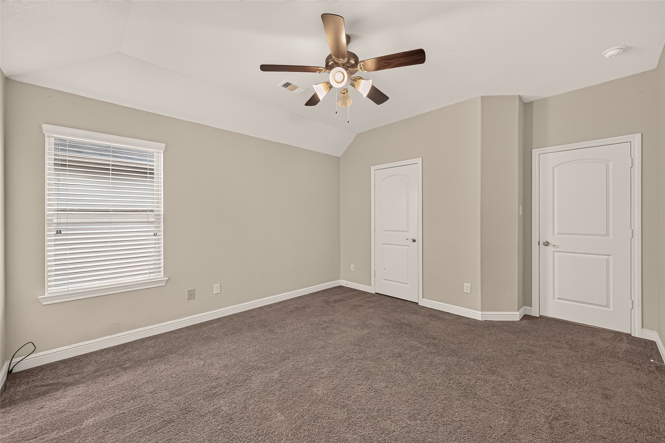 Spacious secondary bedroom featuring plush carpeting, neutral tones, a ceiling fan, abundant natural light, and dual closets.