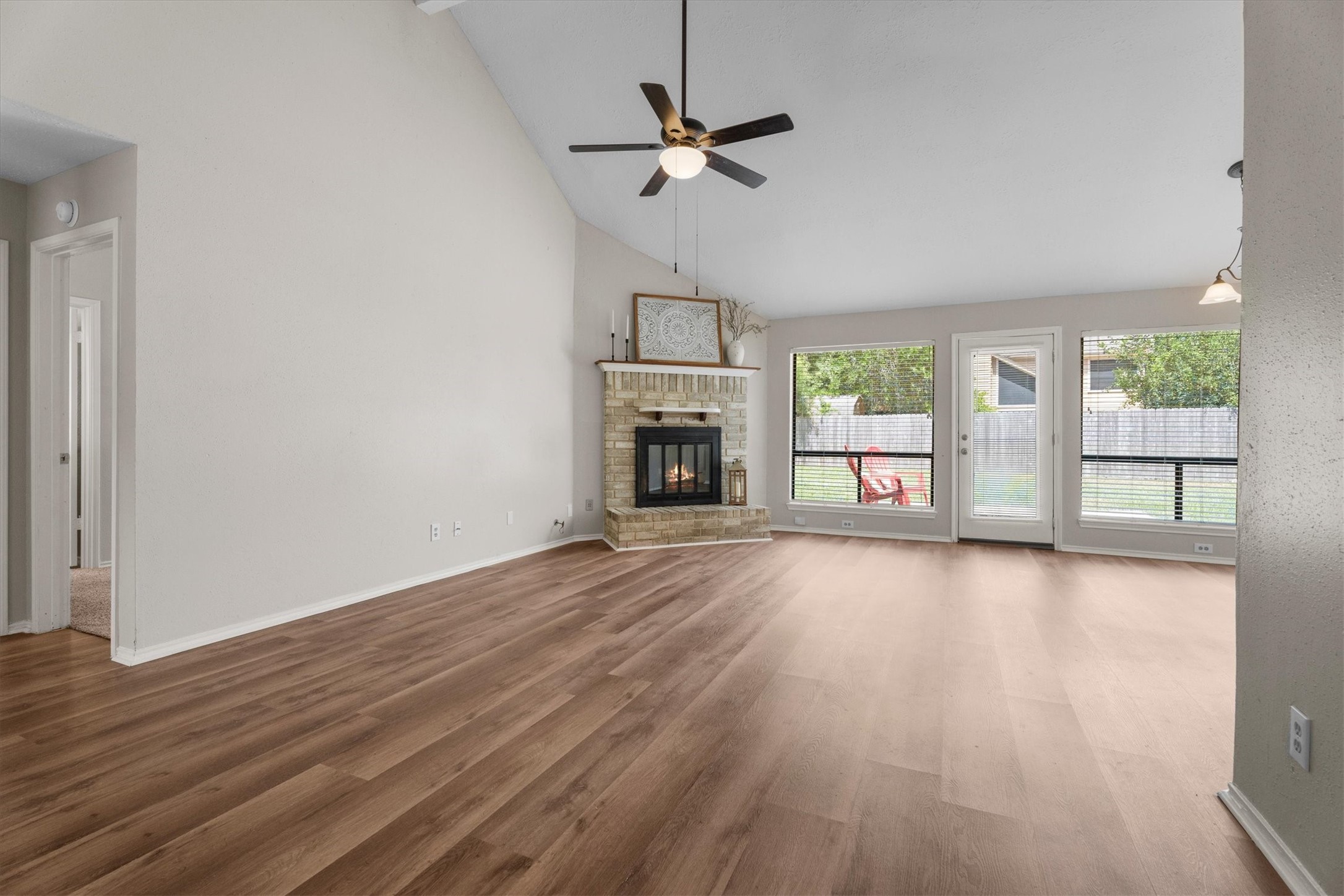 The spacious living area boasts a brick fireplace, vaulted ceiling, and plenty of natural light.