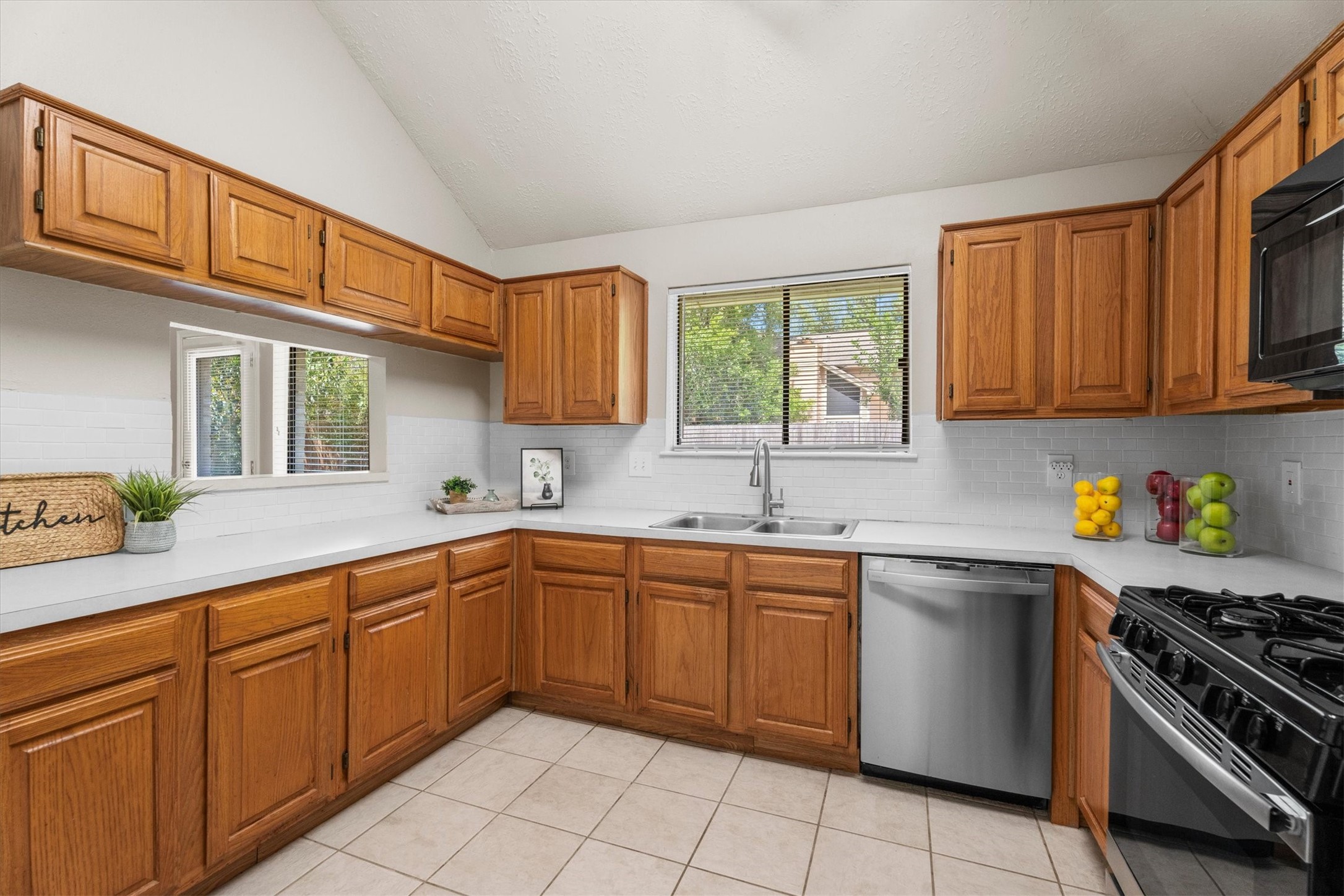 The kitchen workspace has ample counter space, a double sink, a window overlooking the backyard, and plenty of cabinet storage.