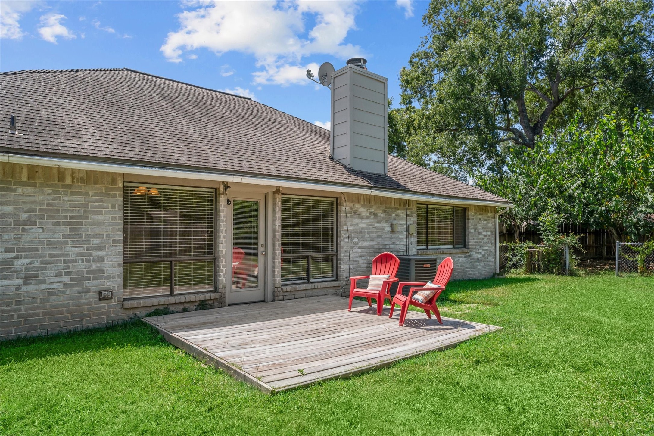 The backyard features a wood deck overlooking the lawn, creating a comfortable spot for outdoor seating and relaxing.