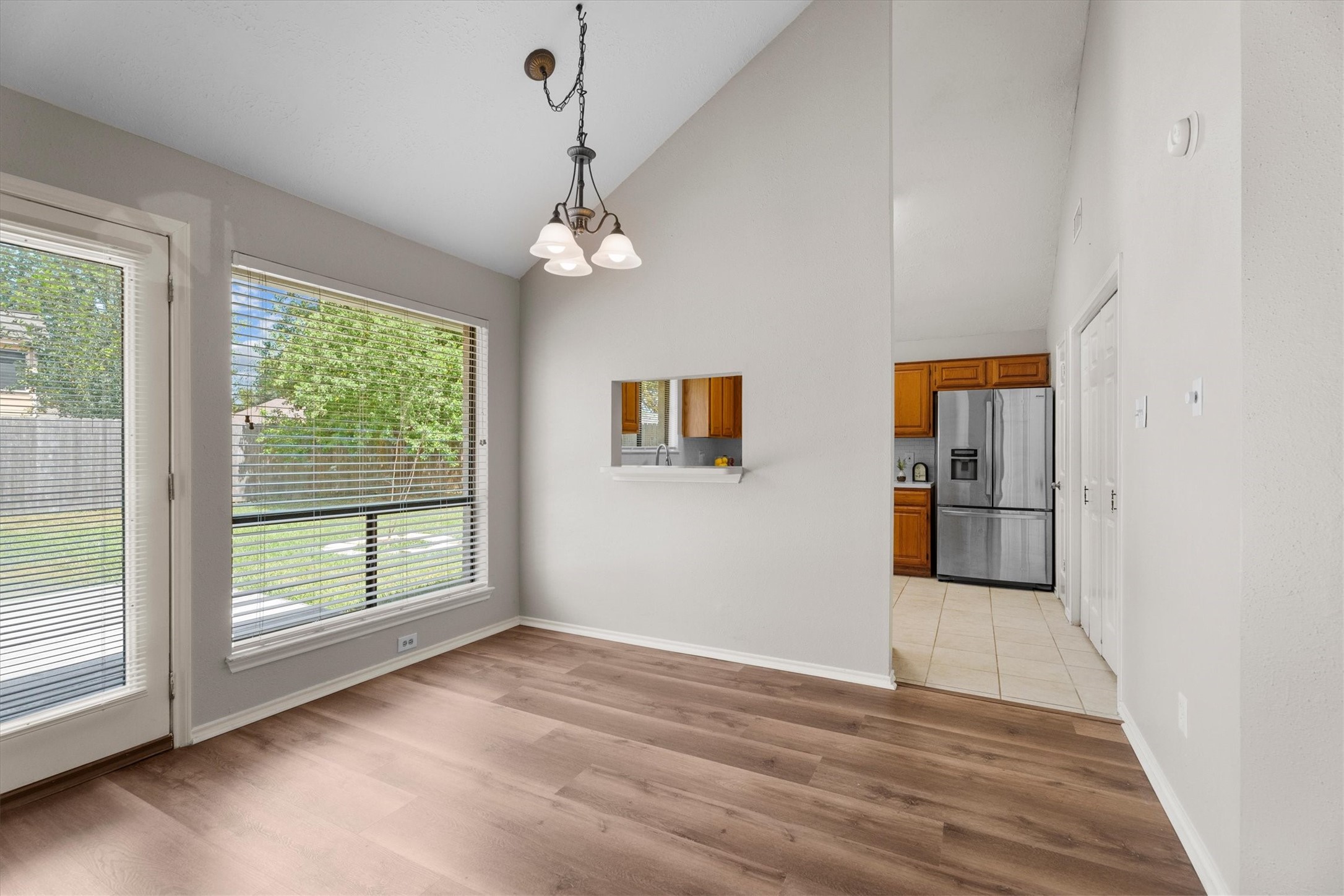Bright breakfast area with large windows, wood-look flooring, and a convenient view into the kitchen.