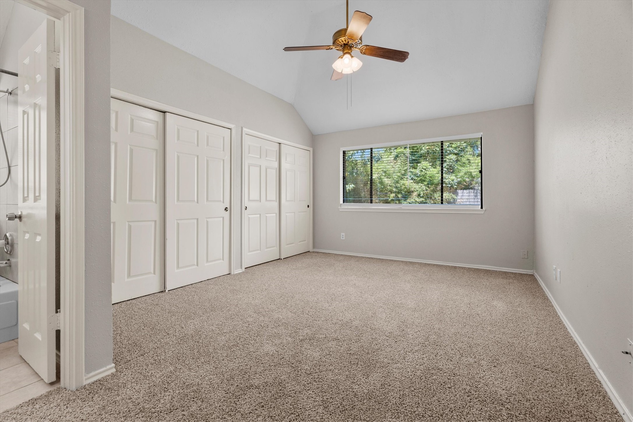 The primary bedroom offers a comfortable retreat with a generous layout, ceiling fan, and large window overlooking the backyard.
