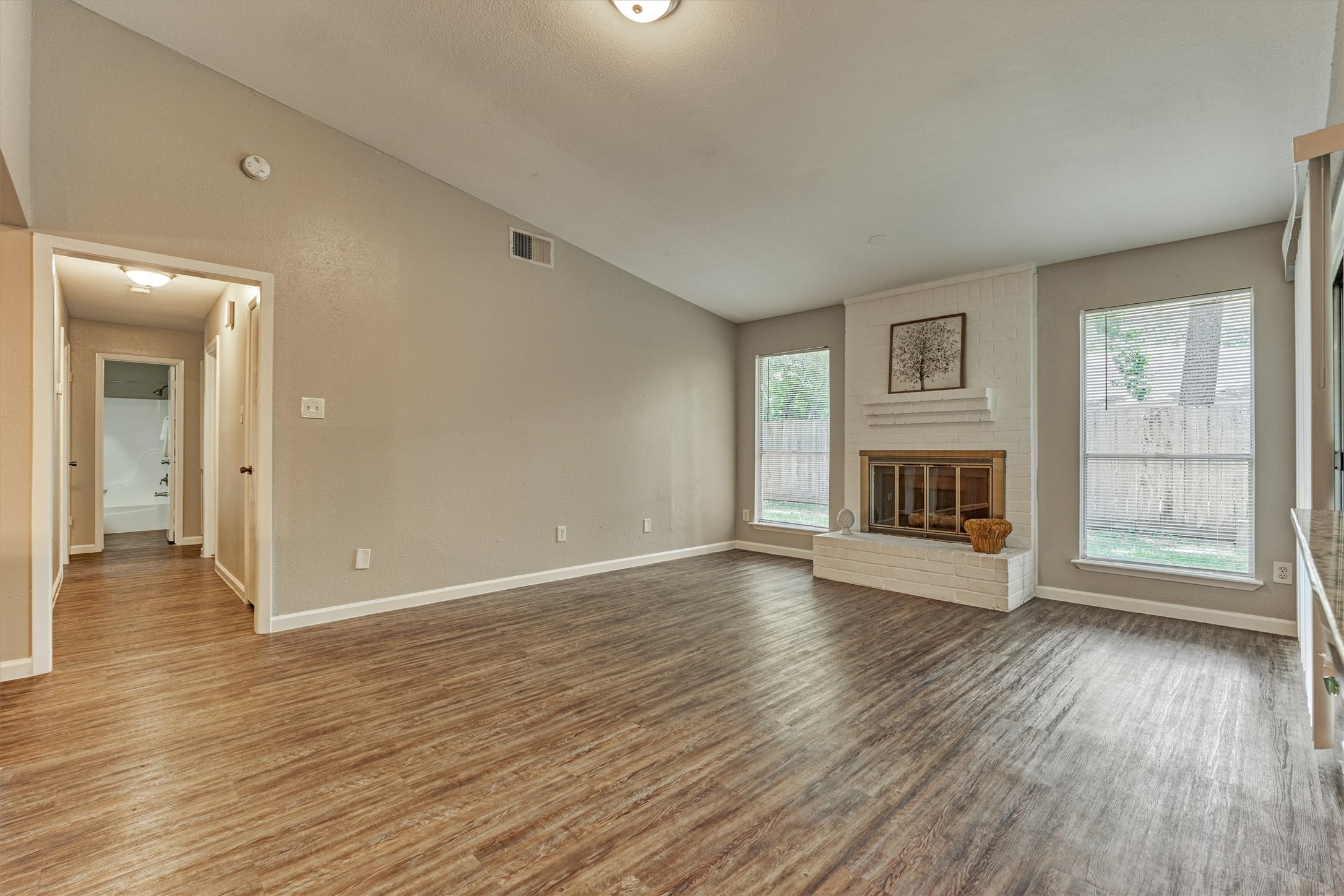 In the living area, large windows flank the gas fireplace and allow natural light into the space.