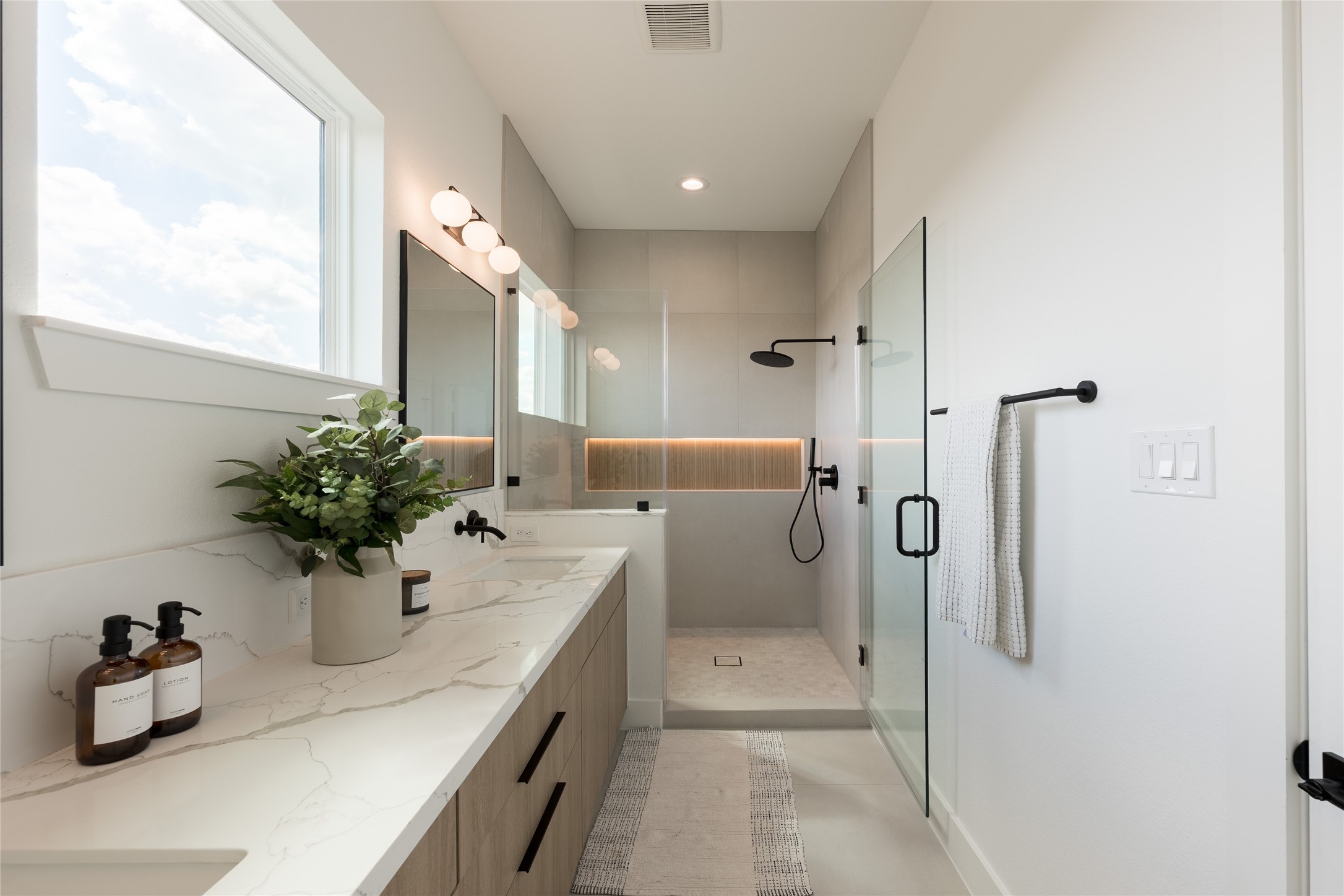Modern sleek bathroom with a spacious walk-in shower, double vanity with elegant fixtures, and abundant natural light.