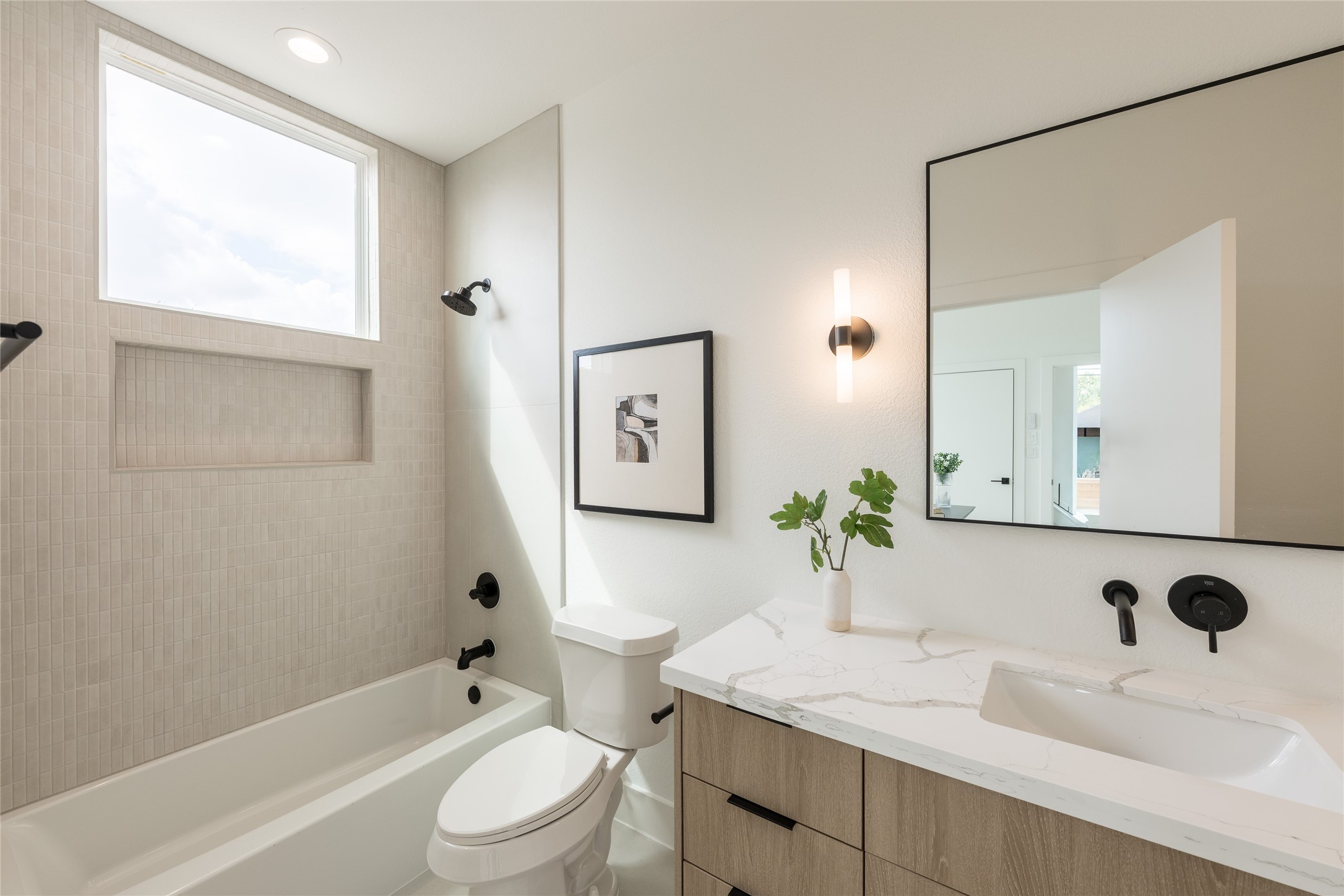 Bright and modern bathroom featuring a sleek vanity with a marble countertop, contemporary fixtures, and a spacious bathtub with a large window for natural light. Bright and modern bathroom featuring a sleek vanity with a marble countertop, contemporary fixtures, and a spacious bathtub with a large window for natural light.