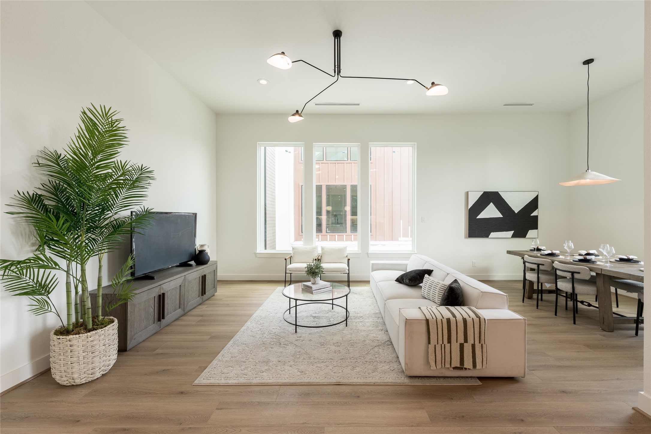 Living room with large windows, and elegant lighting fixture, perfect for both relaxation and entertaining.