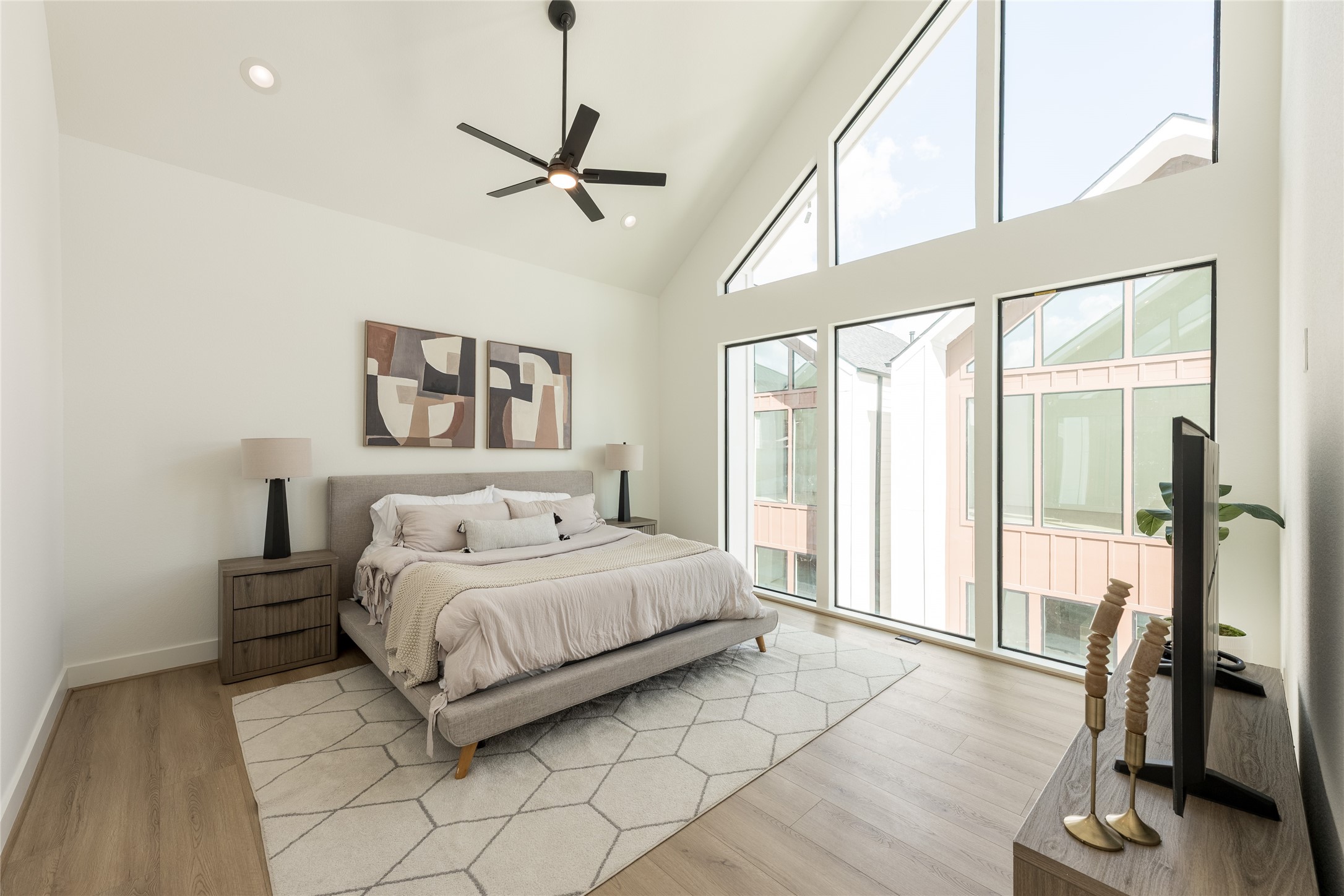 Experience modern elegance in this spacious primary bedroom, featuring vaulted ceilings, expansive windows for abundant natural light