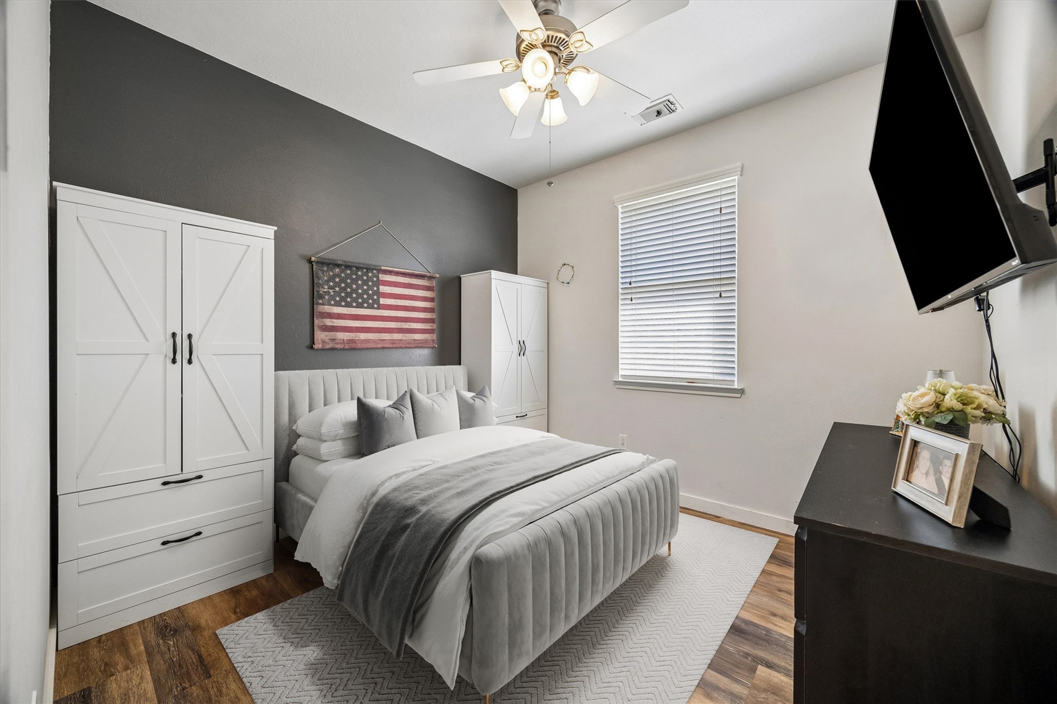 This secondary bedroom features wood-look flooring, a ceiling fan, and a neutral color palette. A comfortable space that can easily accommodate guests or serve as a home office.