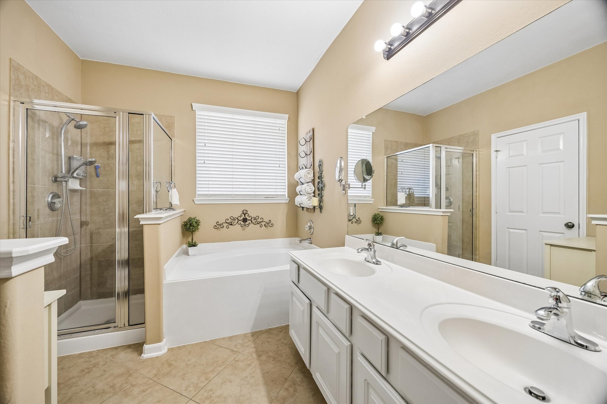 The primary bathroom offers a spacious dual-sink vanity, soaking tub, and separate glass-enclosed shower. Natural light and generous counter space make morning routines feel effortless.