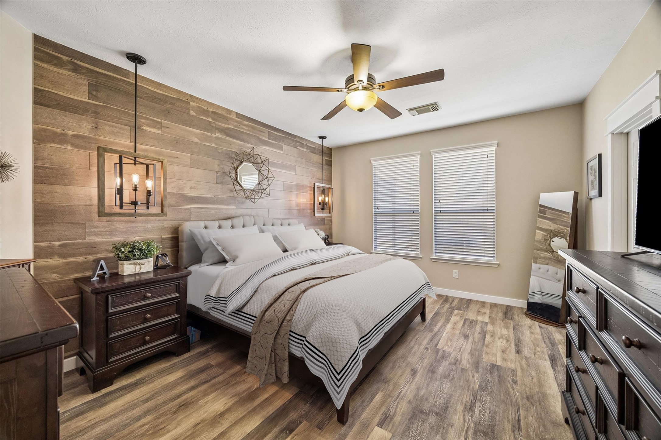 The primary suite feels warm and inviting, featuring beautiful wood-look flooring, a ceiling fan, and a striking wood accent wall. Generous proportions allow plenty of room for bedroom furnishings.