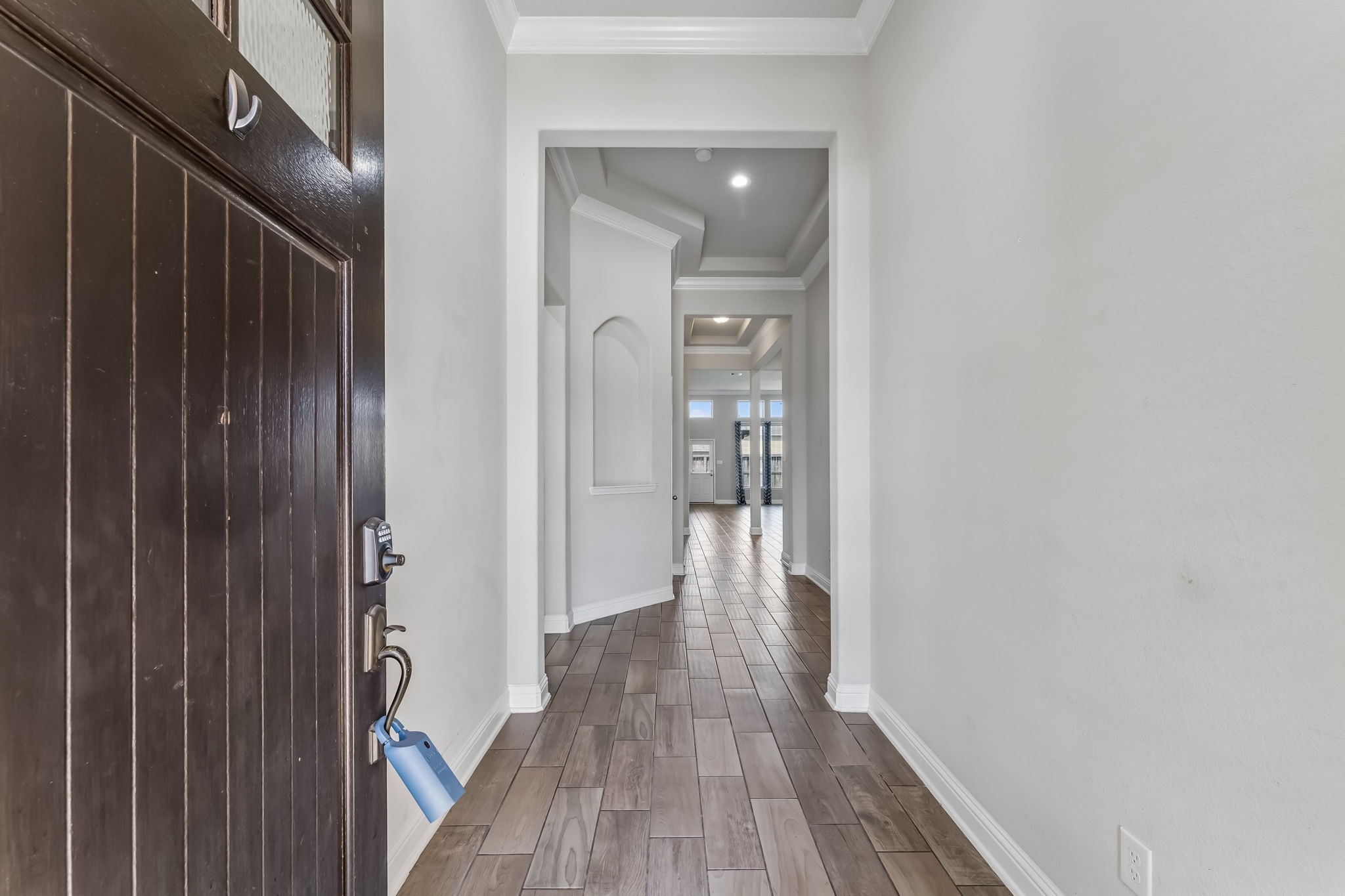 Inviting entryway with elegant wood flooring and high ceilings, leading to an open and spacious living area.