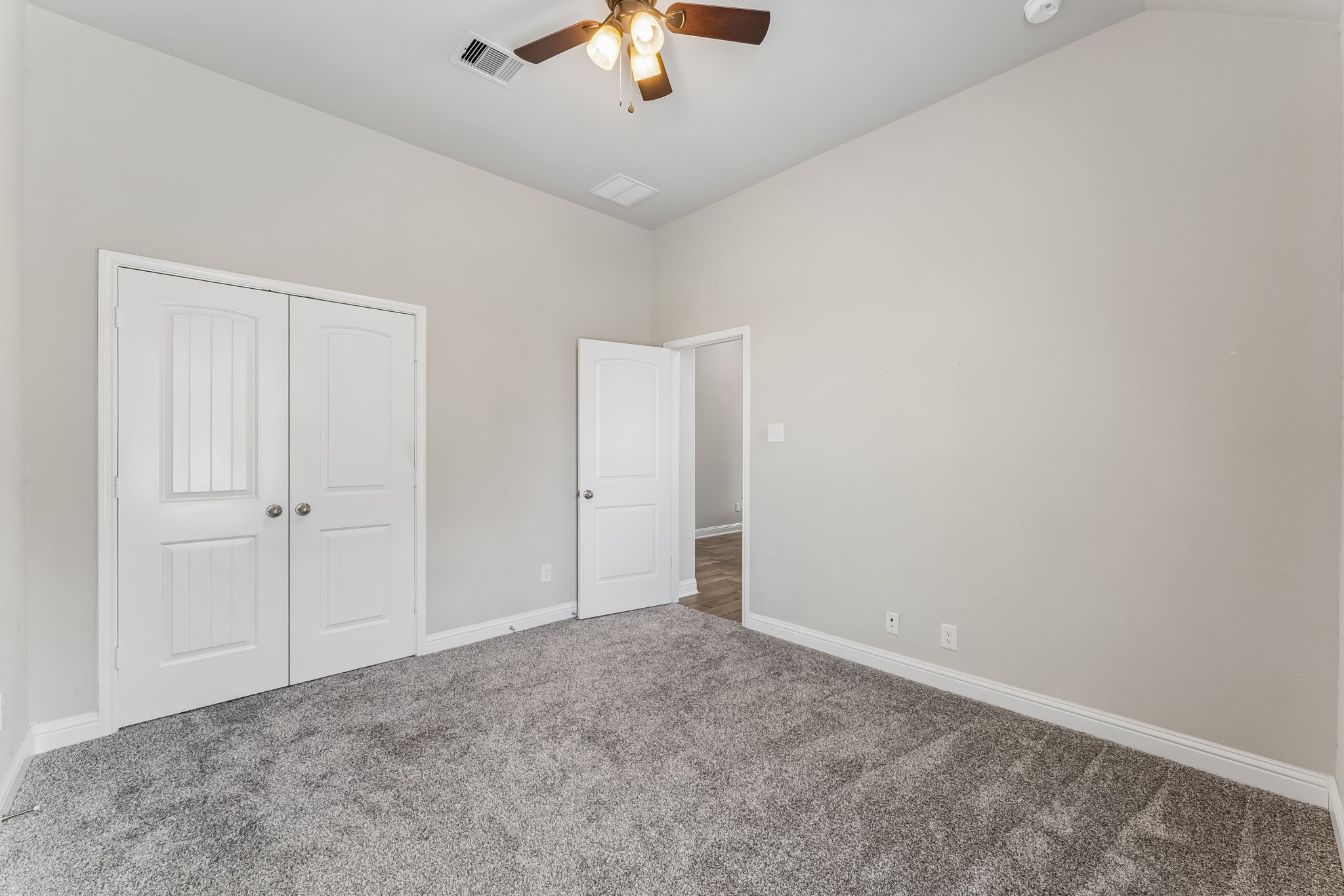 Spacious bedroom with plush carpeting, neutral walls, and a ceiling fan, featuring dual closets for ample storage.