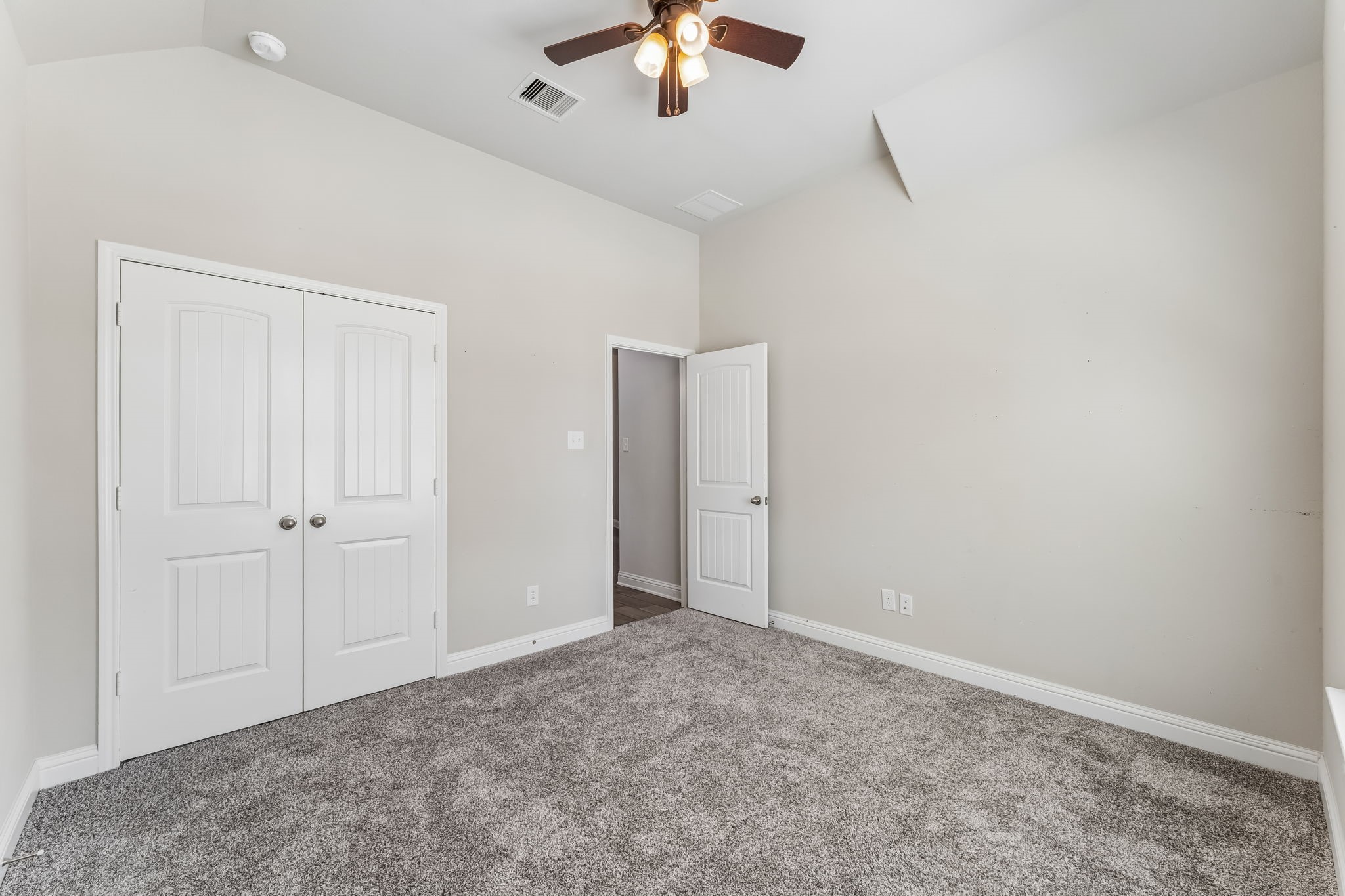Bright and spacious bedroom with plush carpeting, a ceiling fan, and ample closet space for comfortable living.