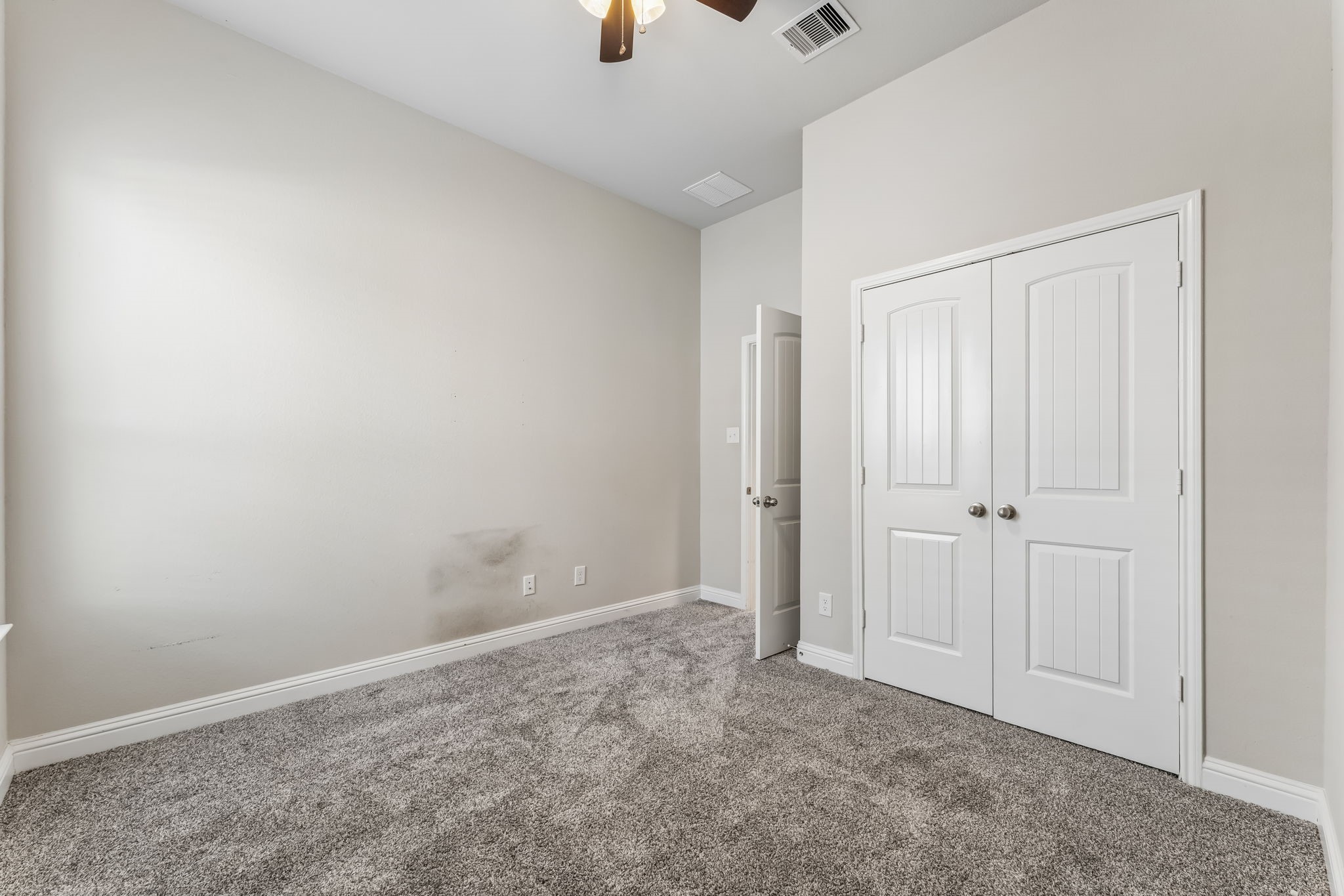 Cozy bedroom featuring plush carpeting, neutral walls, and a spacious double-door closet, perfect for storage.