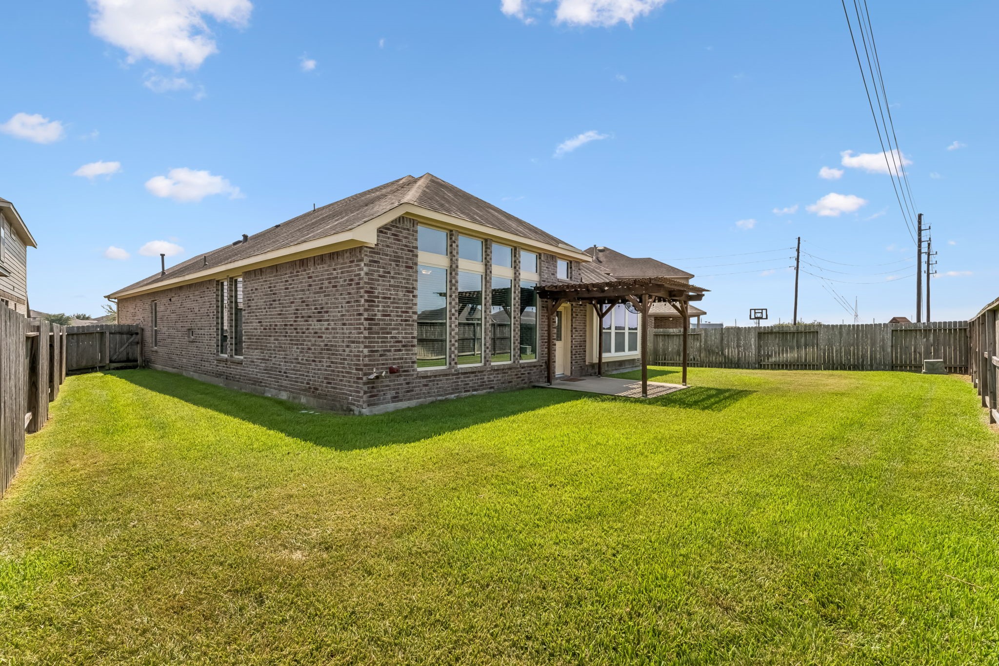 Expansive backyard with a charming pergola, perfect for outdoor gatherings, complemented by a well-maintained lawn and a privacy fence.