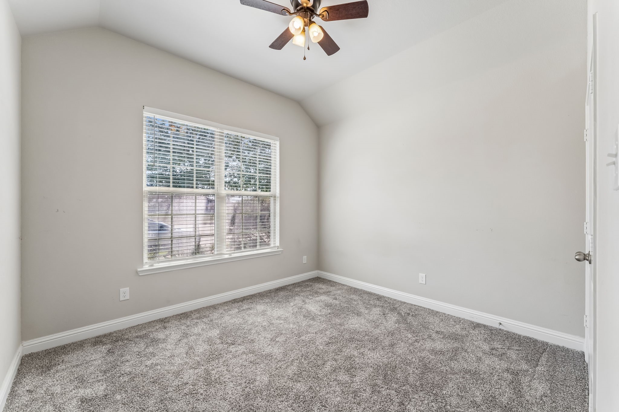 Bright and airy bedroom featuring plush carpeting, a large window for natural light, and a ceiling fan for comfort.