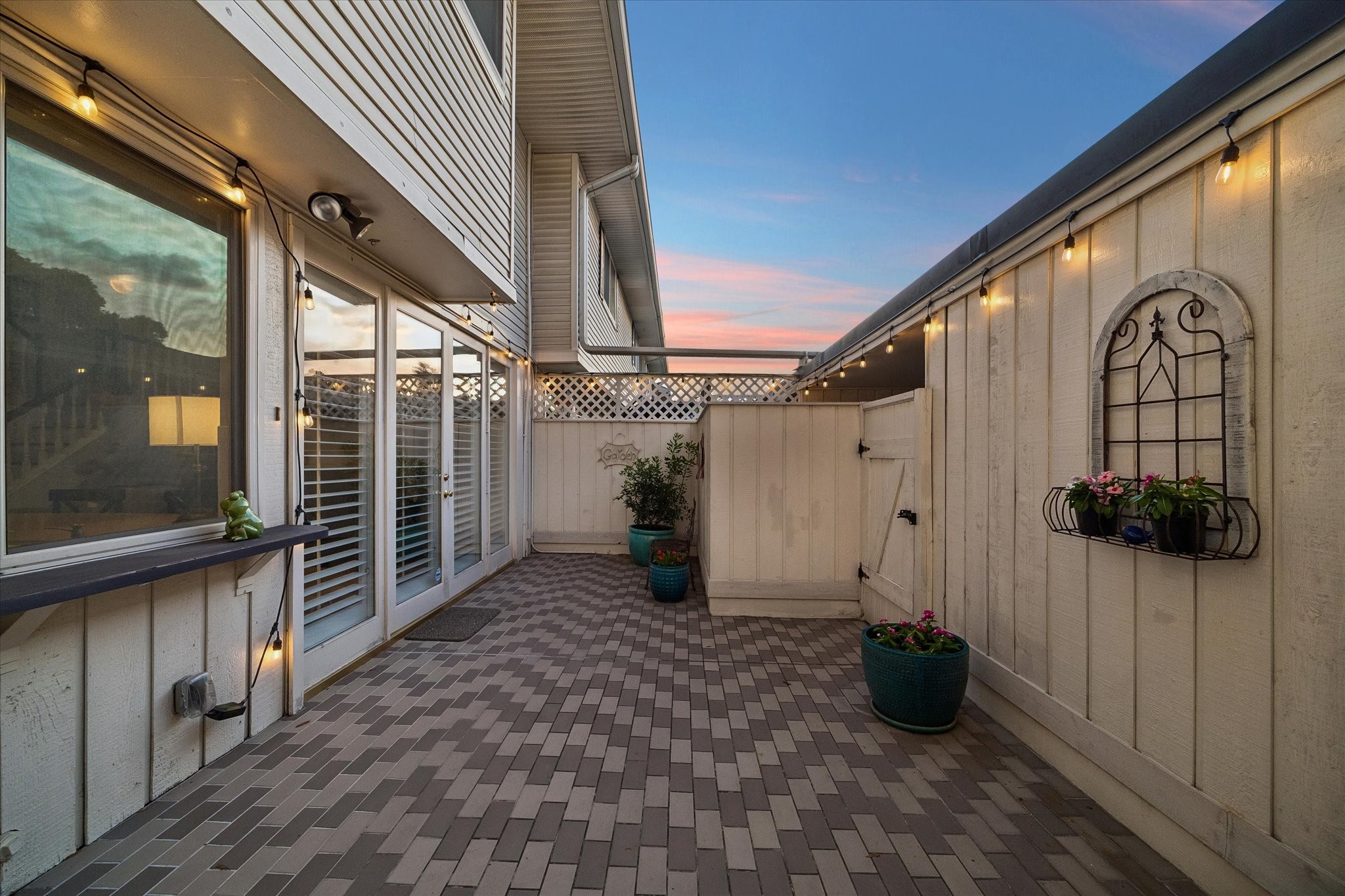 How will you use this spacious private back patio? Seller added the handsome tile and string lights so now you can create your own outdoor oasis! NOTE: outdoor electrical plugs, hidden hose bib, painted privacy fence w/ gate to garage area and concealed A/C unit, and French doors from the grand Family Room/Kitchen Area!