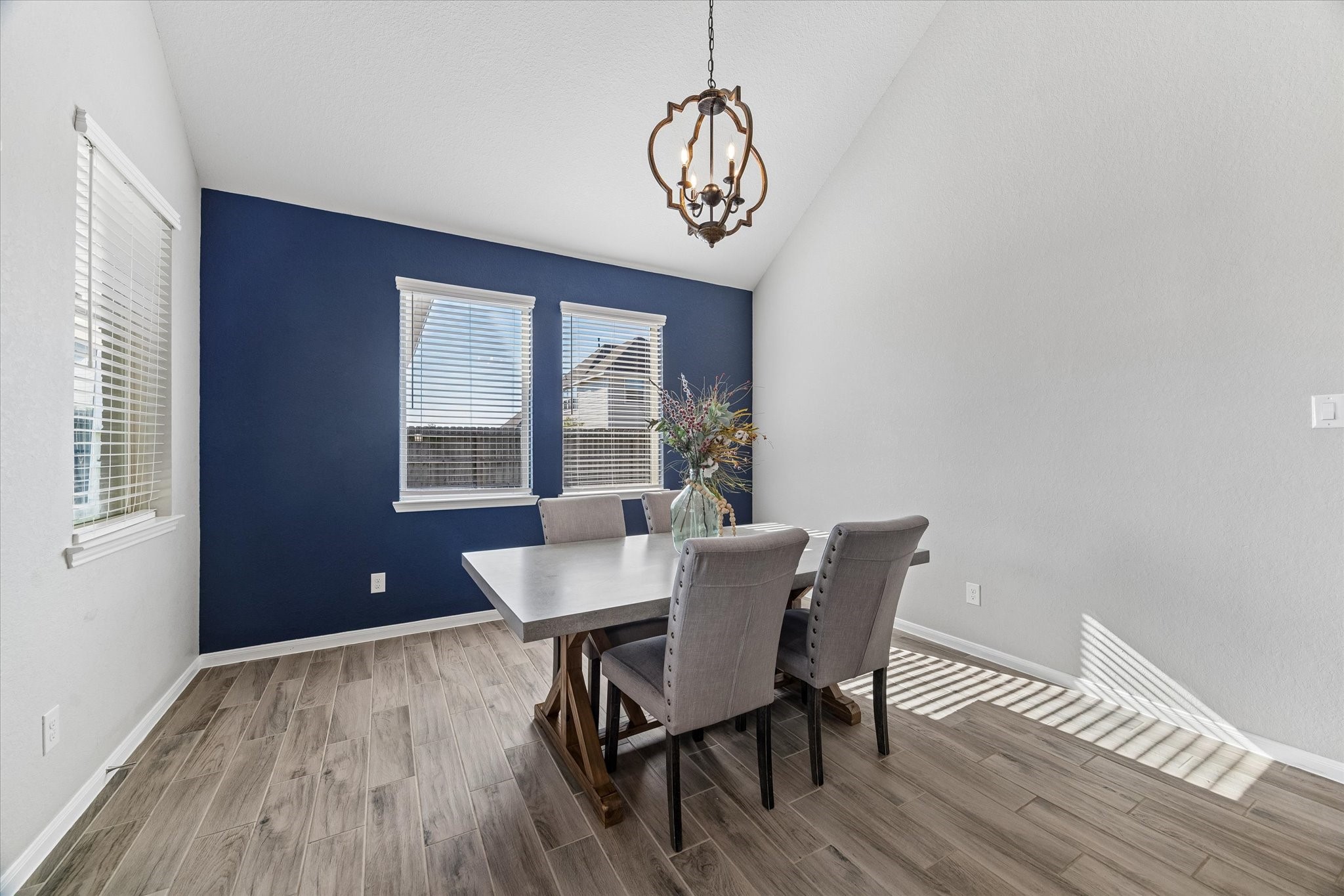A deep blue accent wall and statement chandelier give the dining room a distinctive backdrop for everyday meals and special celebrations.