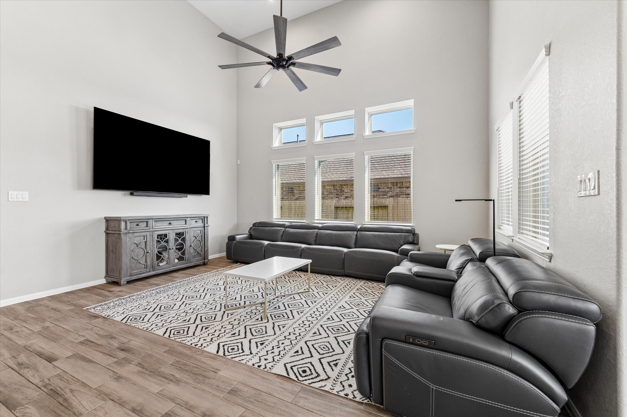 Soaring ceilings, abundant natural light, and a spacious seating area make the living room an inviting place to gather.