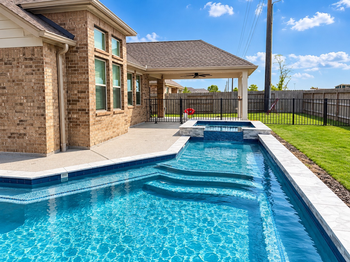 Added in 2025, the heated pool features a generous tanning ledge trimmed in mosaic glass tile, an attached hot tub, and a depth reaching six feet for your own backyard escape.
