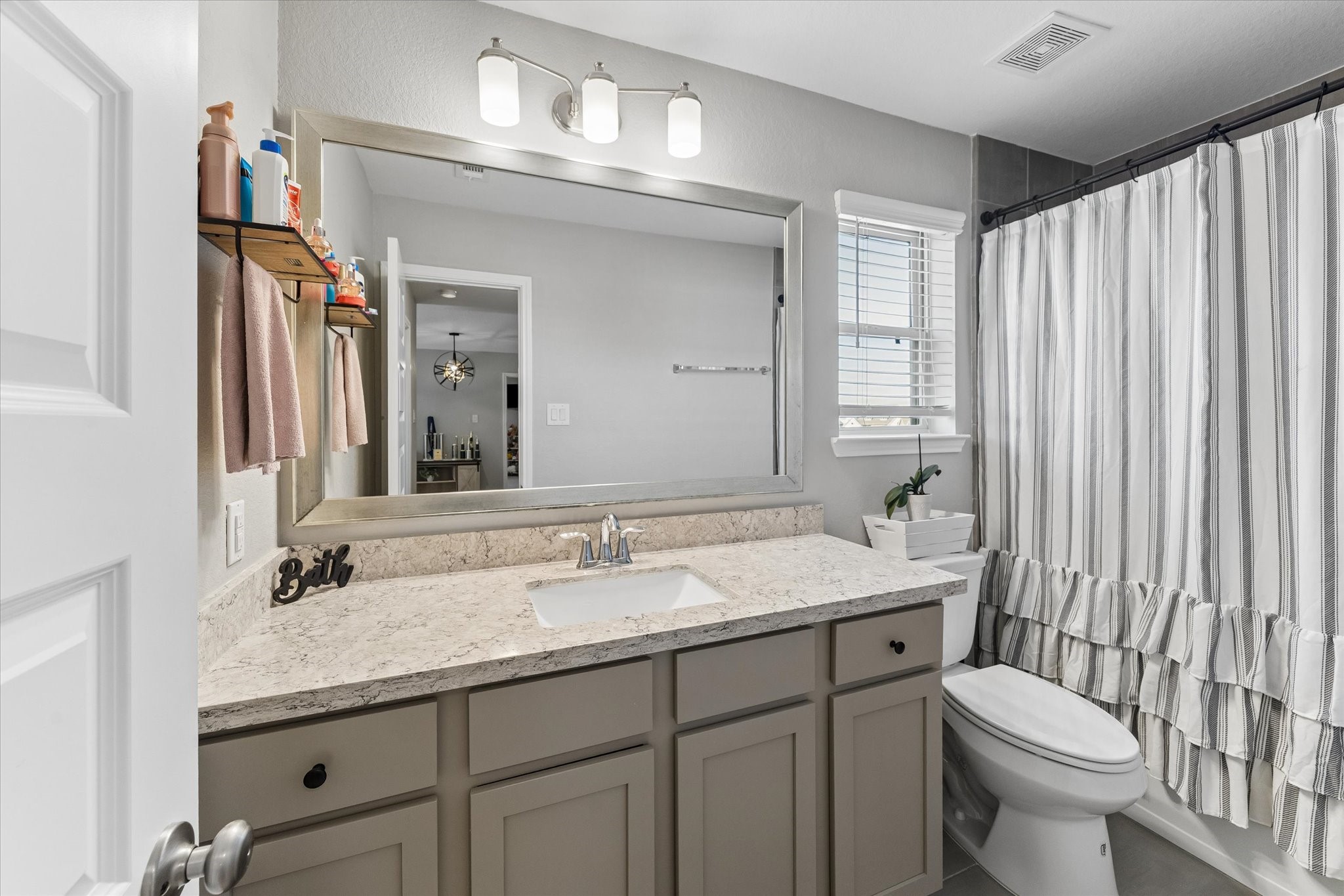 Conveniently located near the upstairs secondary bedrooms, this full bathroom offers vanity storage, a wide mirror, and a tub-and-shower combination.