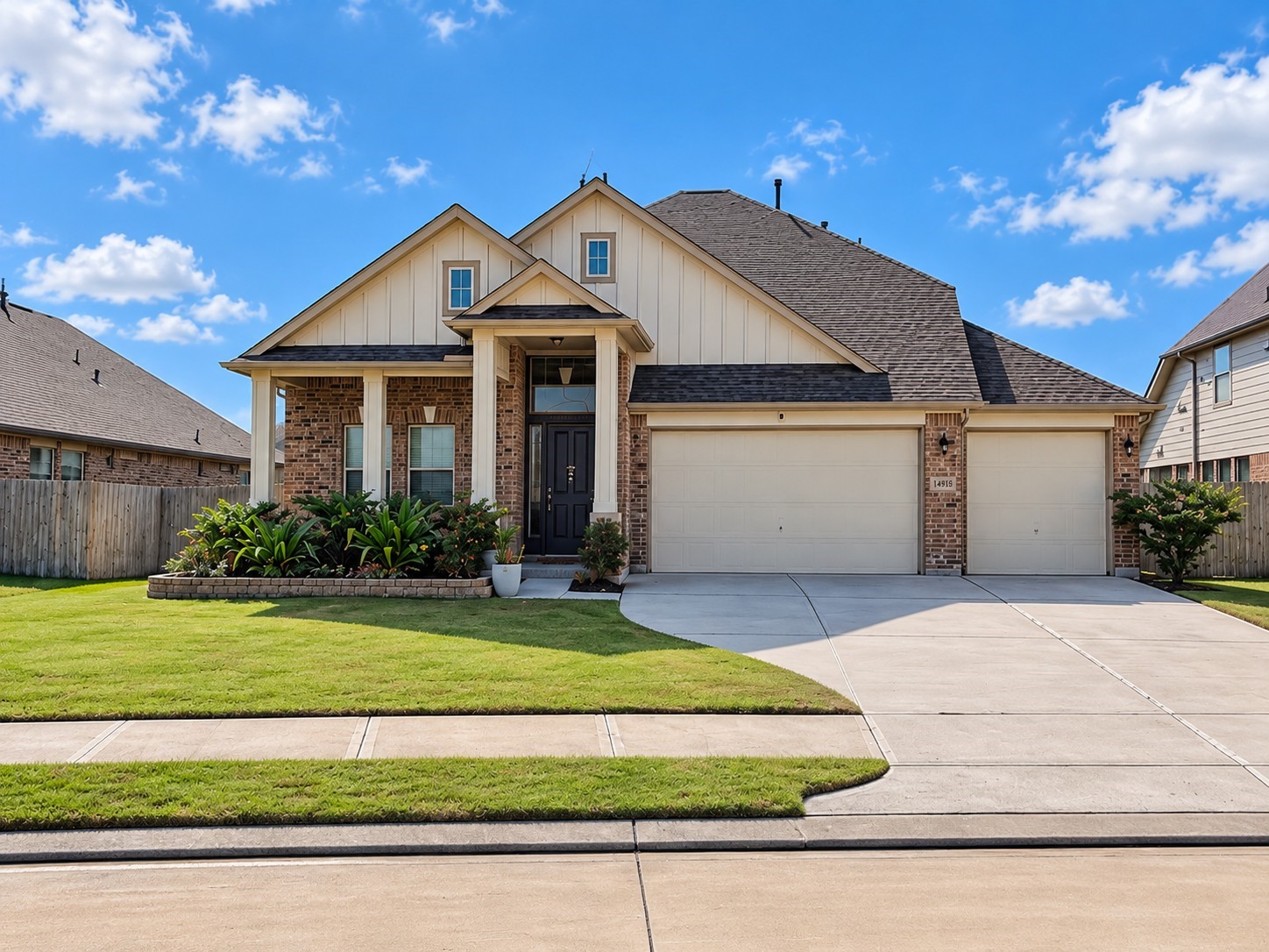 Stone-edged landscape beds frame the brick exterior, while board-and-batten gable accents, paneled porch columns, and brick paver flooring add character to the welcoming entry.