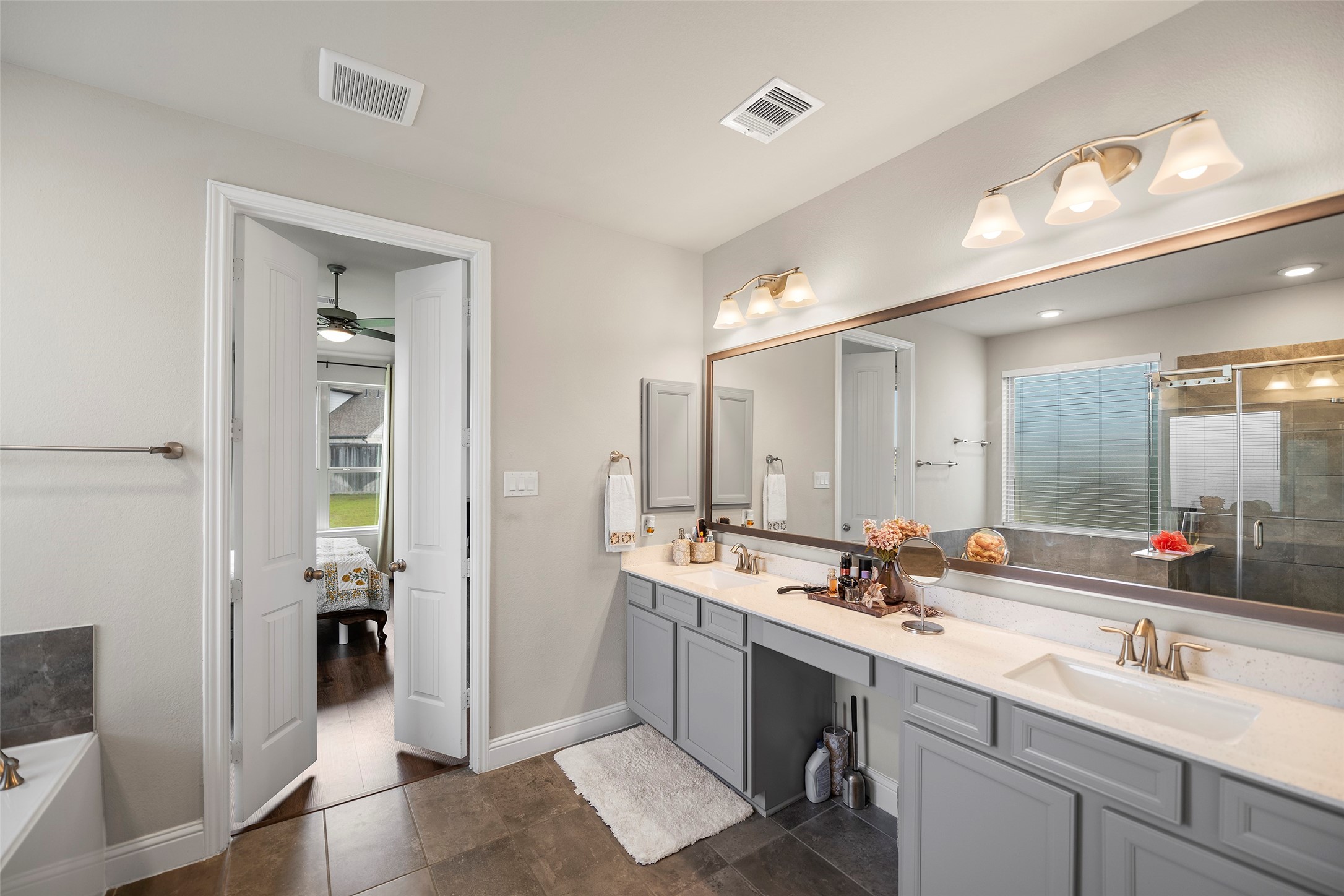 Another view of the primary bathroom highlighting the extended vanity and separate shower.