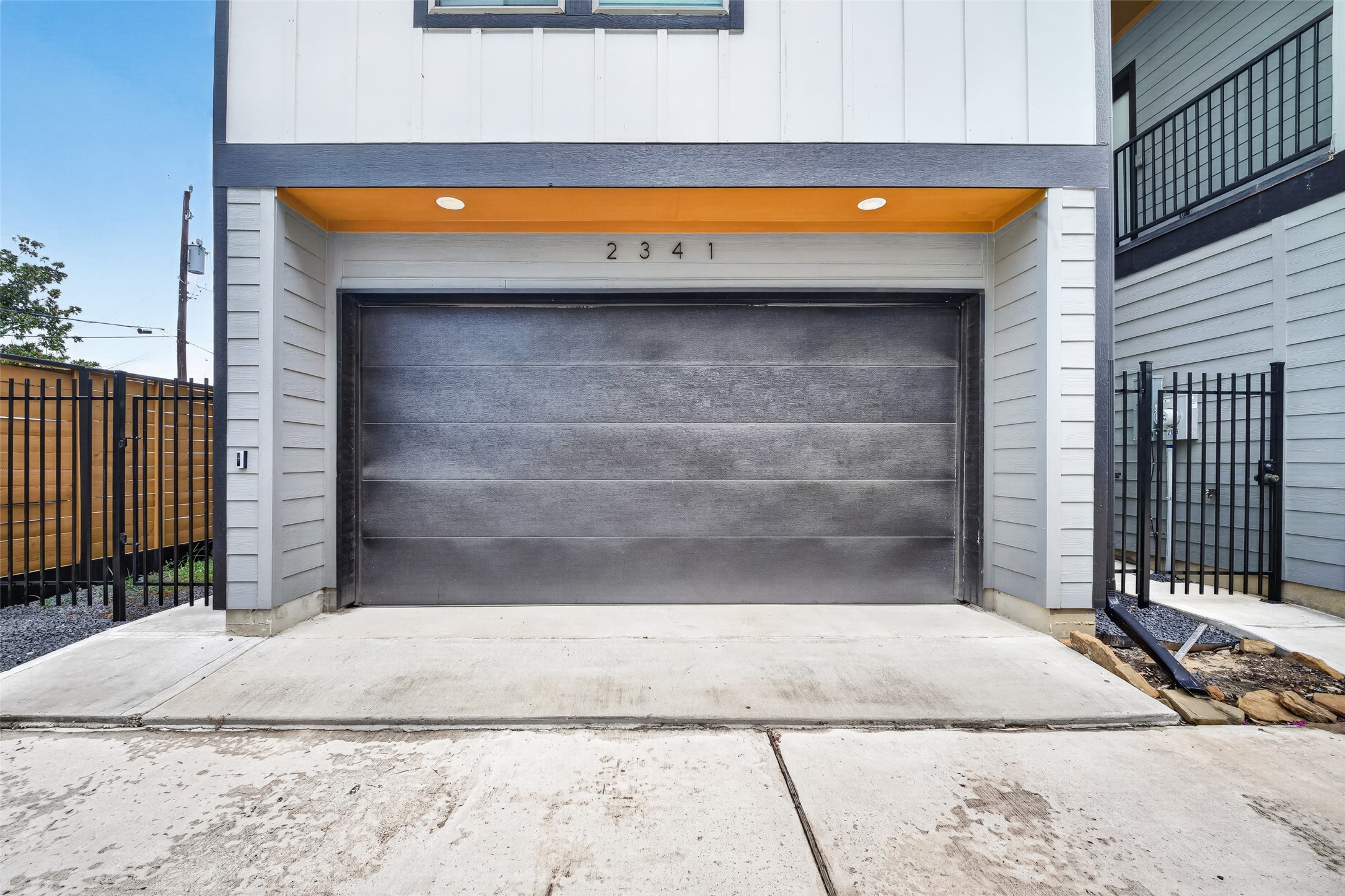 Clean exterior lines lead down to the two-car garage, illuminated by integrated overhead beam lighting. Clean exterior lines lead down to the two-car garage, illuminated by integrated overhead beam lighting.