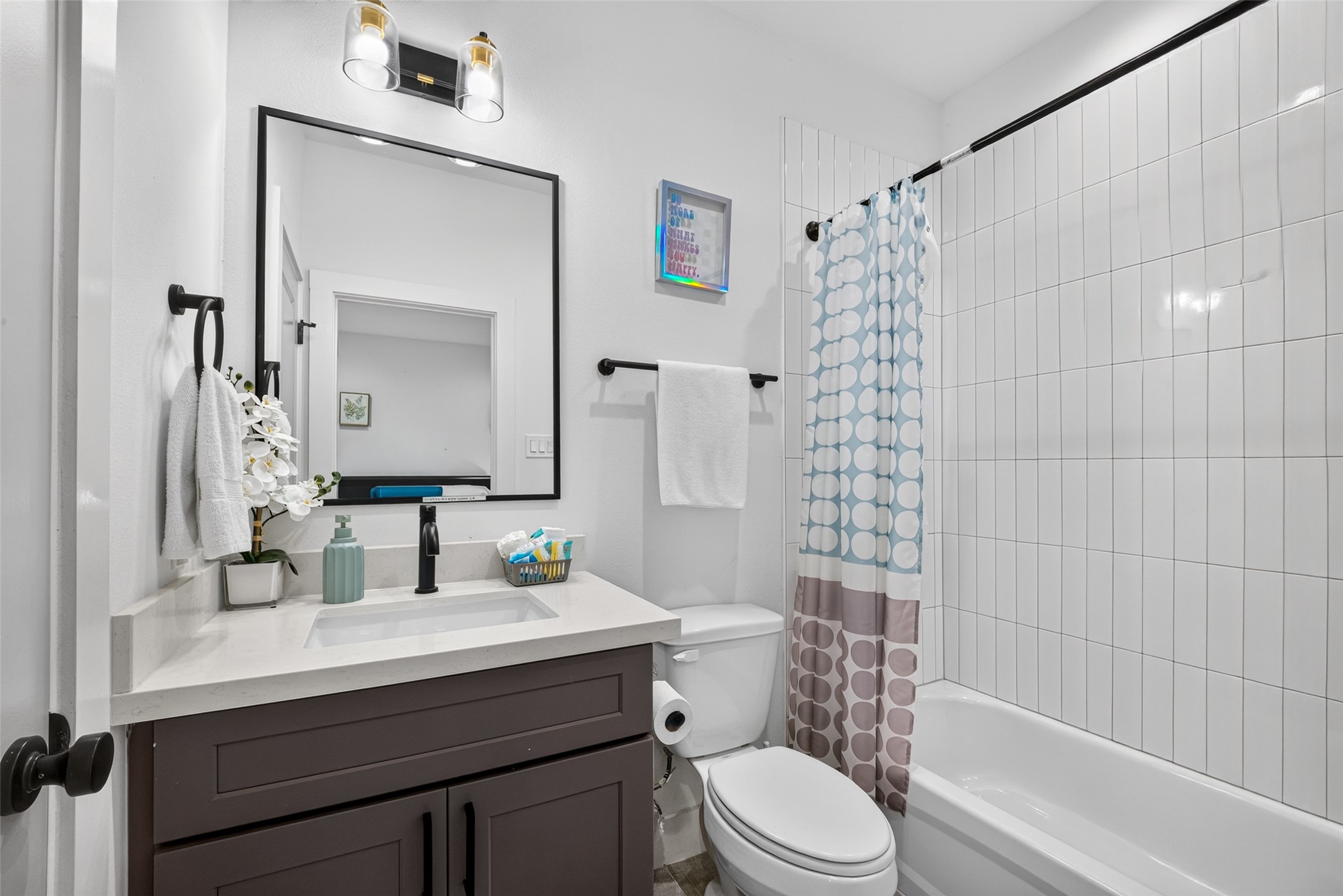 The first bedroom's full bath features a clean vanity setup and a classic shower-tub combination, carrying the home's clean, contemporary aesthetic into the private quarters. The first bedroom's full bath features a clean vanity setup and a classic shower-tub combination, carrying the home's clean, contemporary aesthetic into the private quarters.