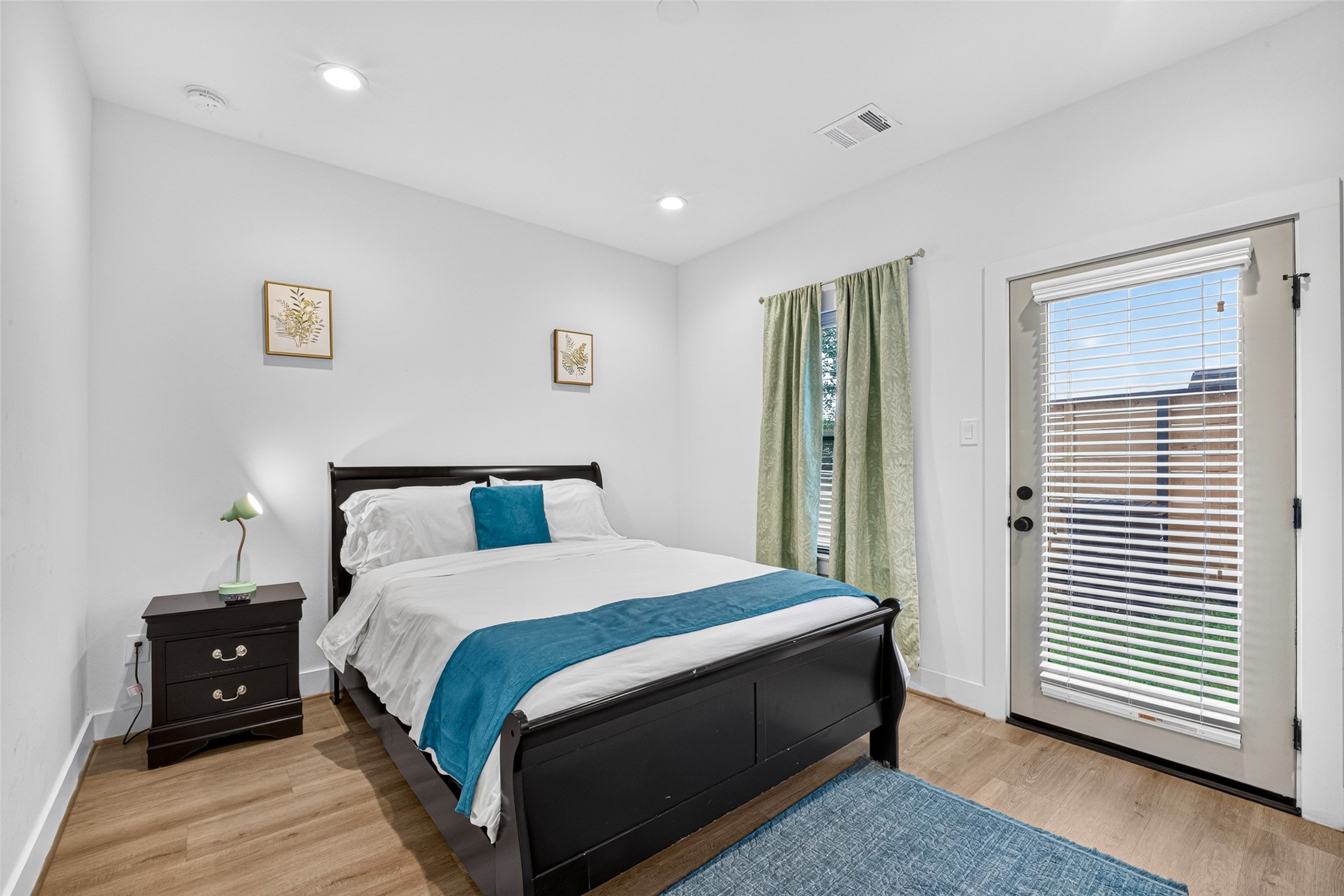 Sunlight streams across warm hardwoods in this ground-floor bedroom, complete with a glass-paneled door that opens directly to the private yard space. Sunlight streams across warm hardwoods in this ground-floor bedroom, complete with a glass-paneled door that opens directly to the private yard space.