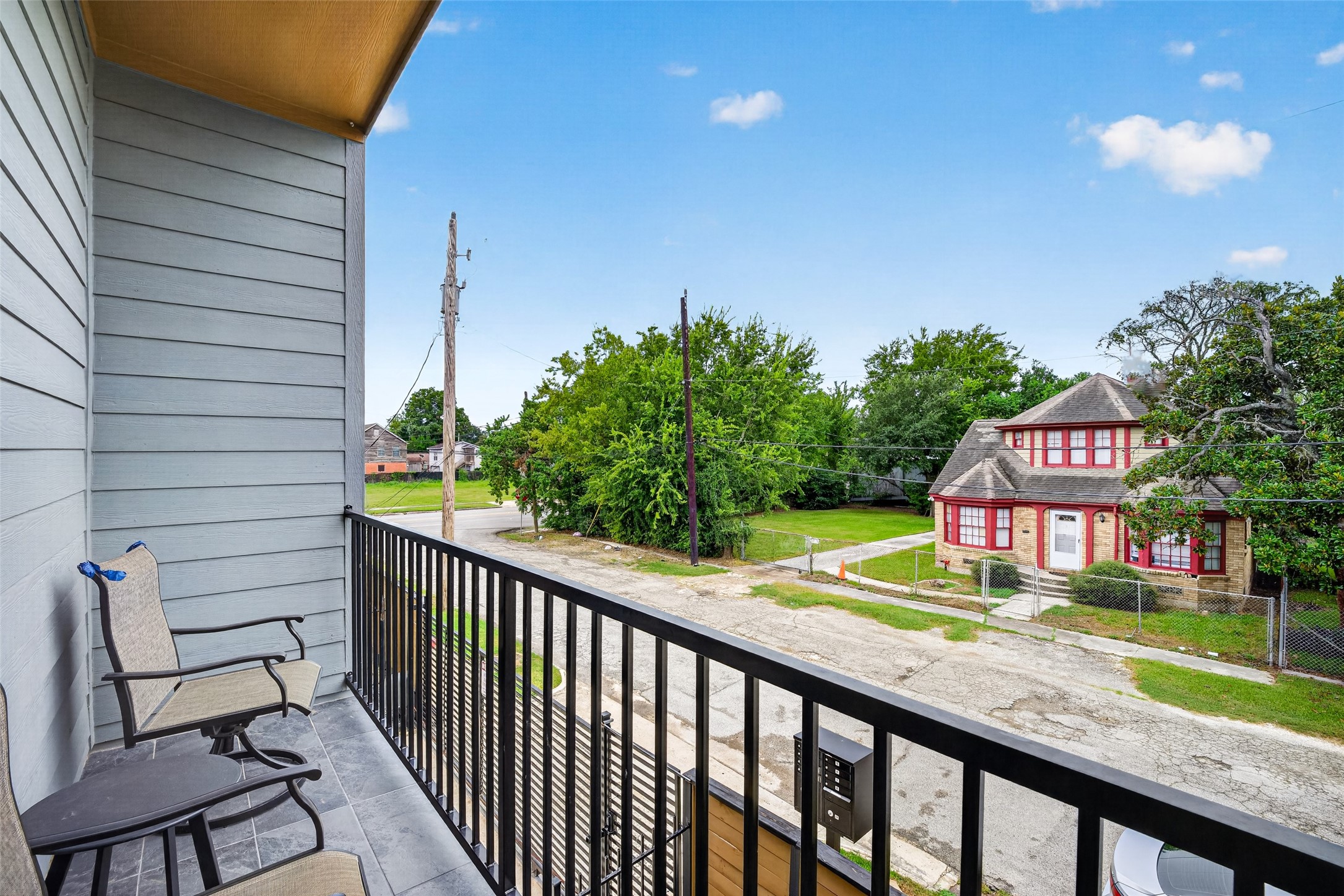 The balcony provides a quiet vantage point over the tree-lined neighborhood streetscape, offering ample space for lounge seating.