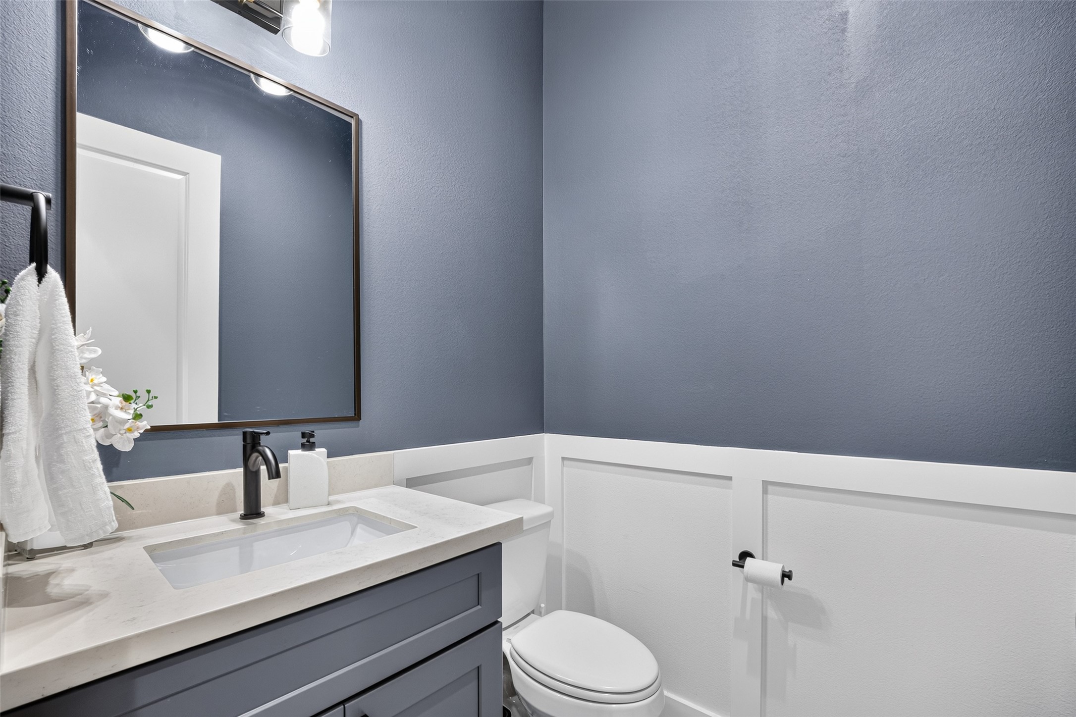Soft gray and bright white tones create a sophisticated backdrop for this guest powder room and its modern vanity.