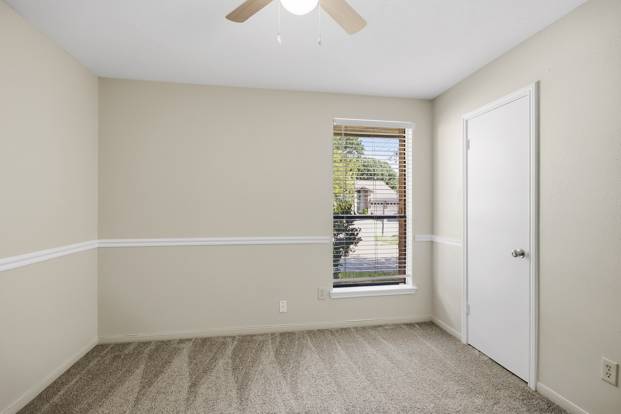 Third bedroom featuring carpet flooring, a ceiling fan, and a window providing natural light.