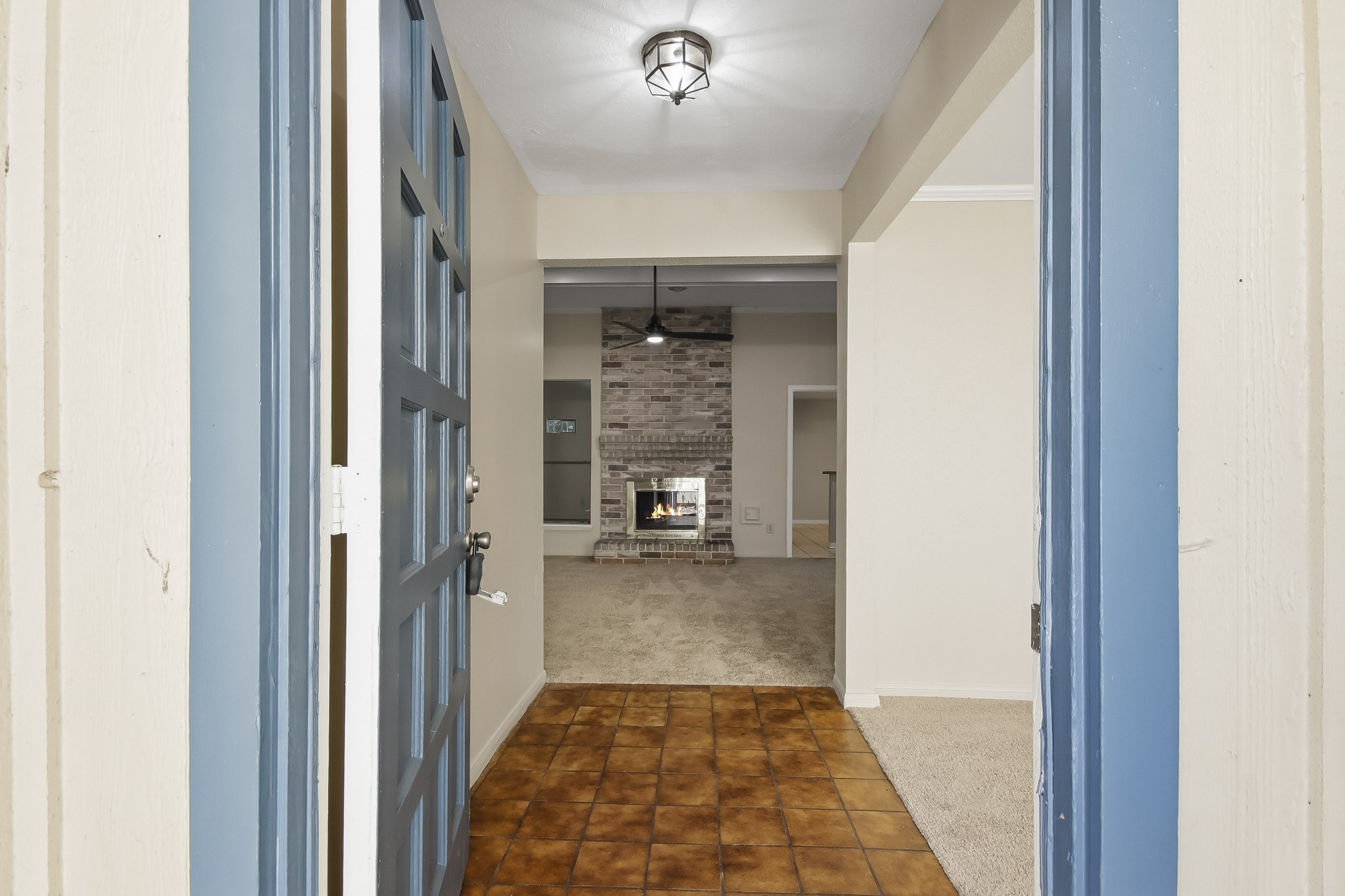 Step inside to a tiled entryway leading into the living room, featuring a brick fireplace.