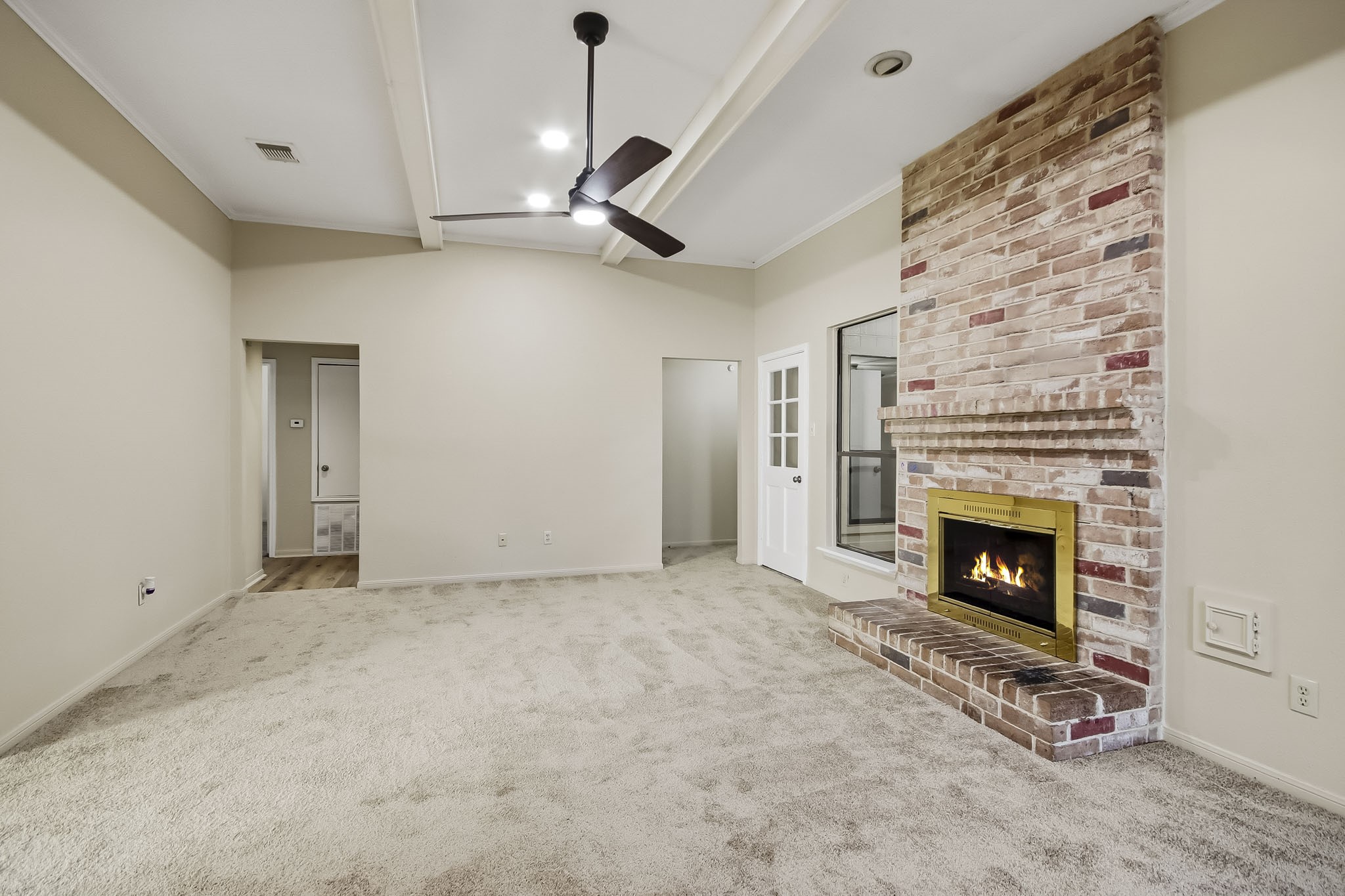 Spacious living room featuring a floor-to-ceiling brick fireplace, high ceilings, and a ceiling fan.