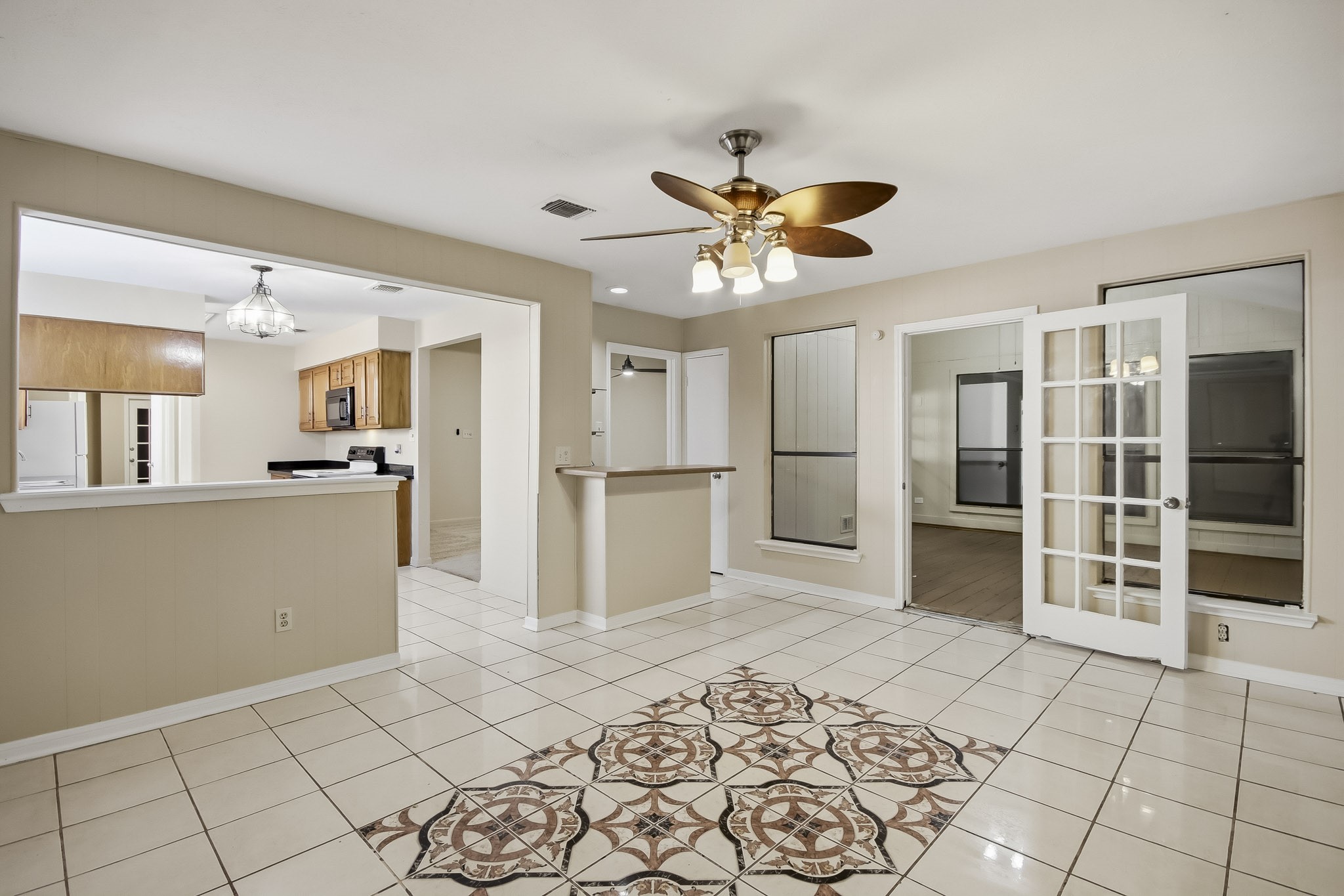 Spacious breakfast area just off the kitchen, featuring decorative tile flooring and French doors leading to an additional flex space.