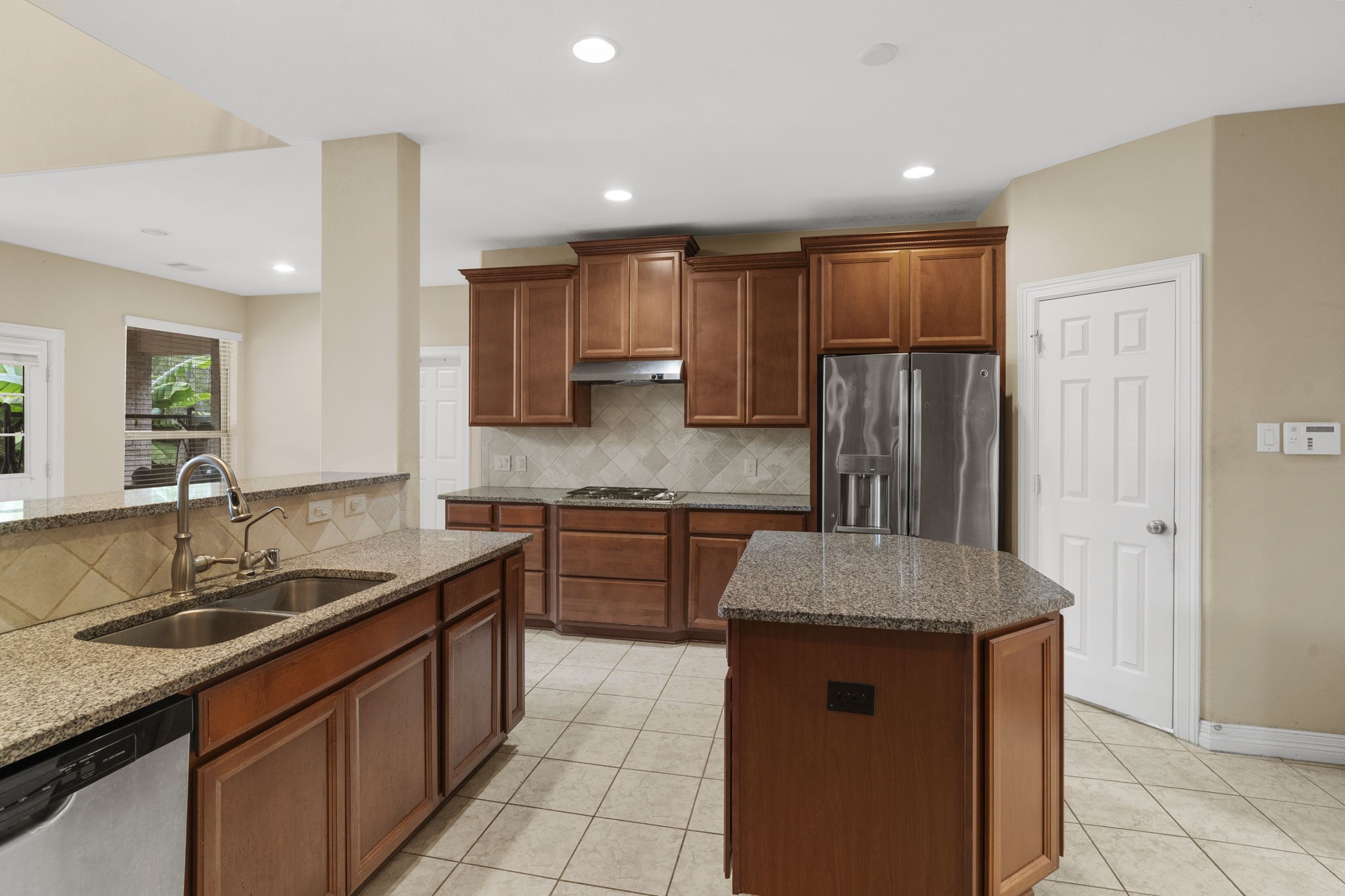 Durable granite countertops pair beautifully with a travertine tile backsplash and stainless steel appliances.