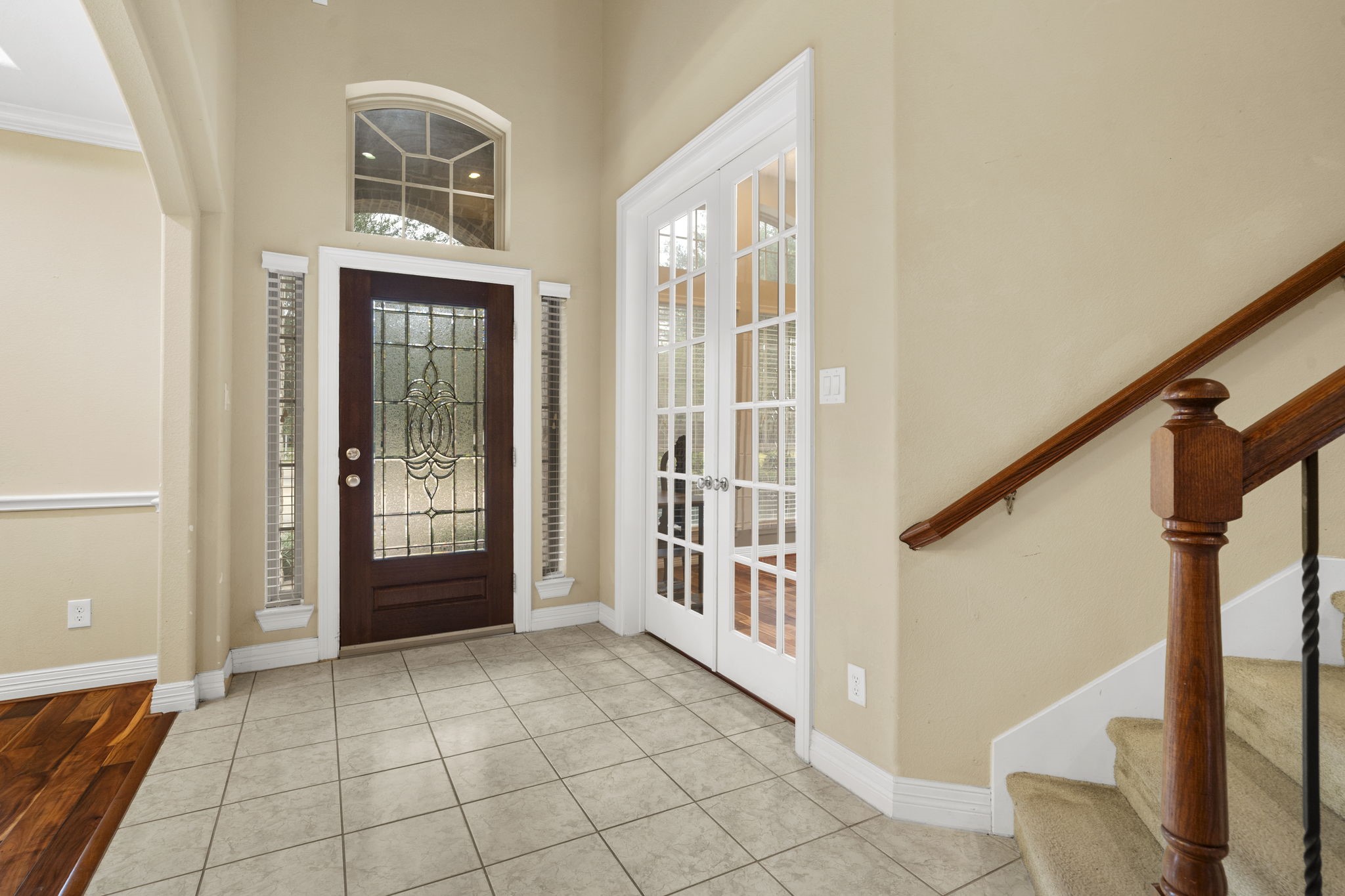 Wood front door accented with decorative leaded glass, a transom window above, and sidelights on either side.